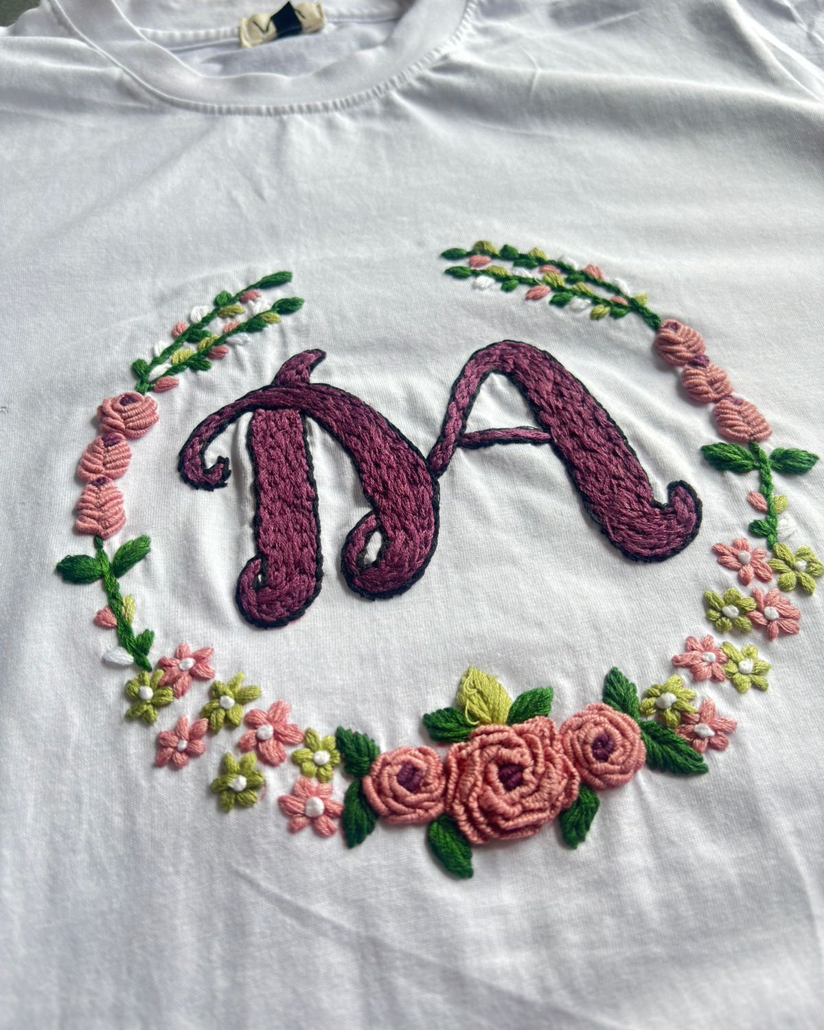 Letter embroidery design - the letter A hand-stitched inside a floral wreath on a white cotton shirt