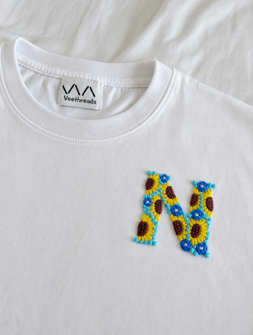 Custom initial stitched from sunflowers and small blue flowers on white cotton, by Vee Threads