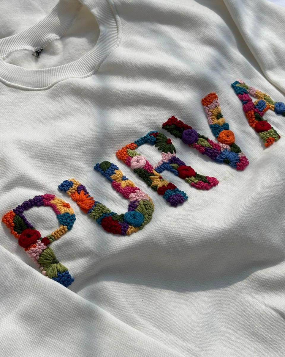 Close-up of embroidered name on heavyweight cotton sweatshirt, showing clean threadwork and premium fabric texture.