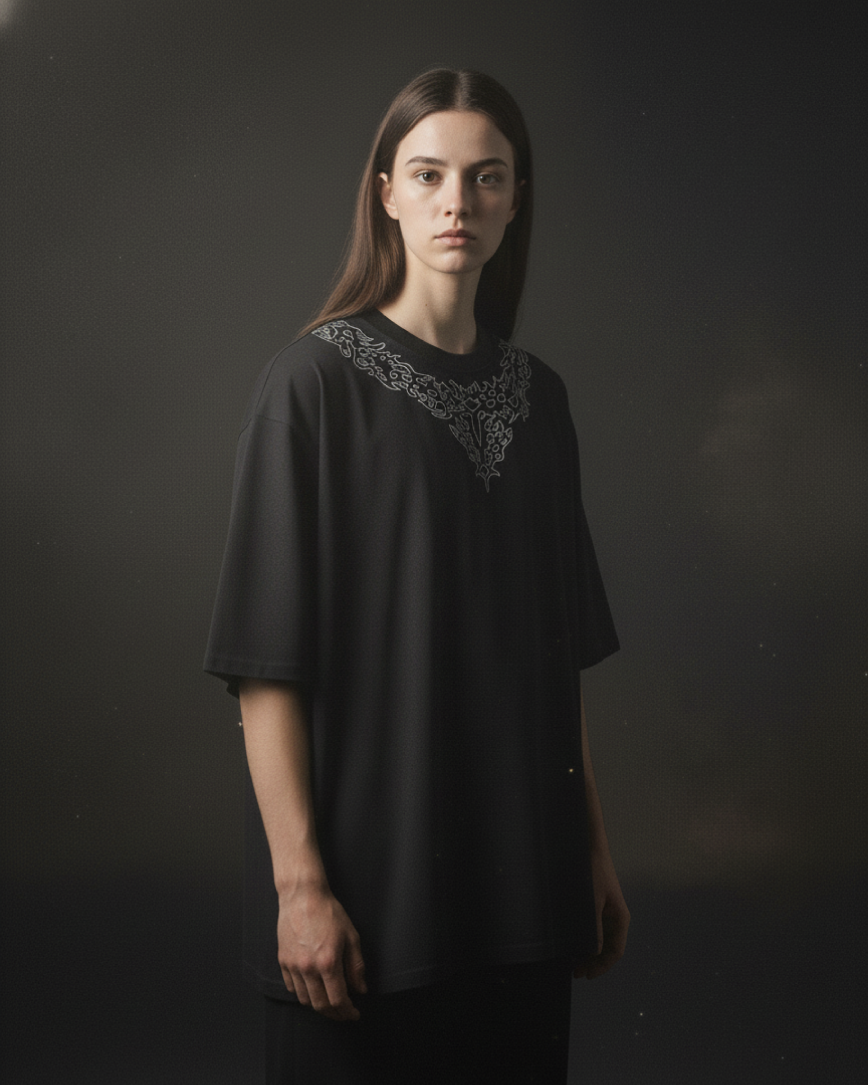 Person wearing a black dress with intricate detailing on a dark background