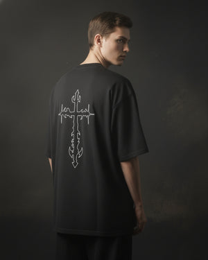 Person wearing a black t-shirt with a white graphic design on the back against a dark background