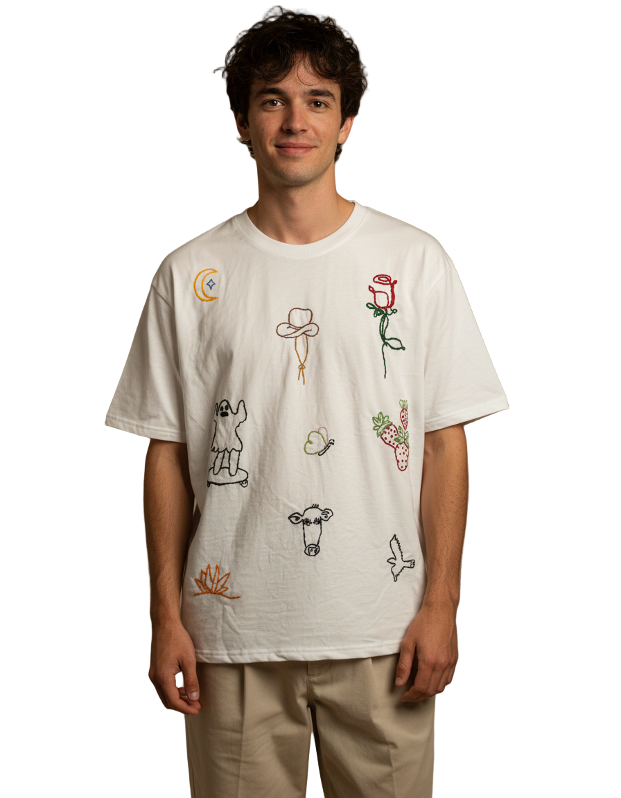 Person wearing a white t-shirt with embroidered designs on a beige background