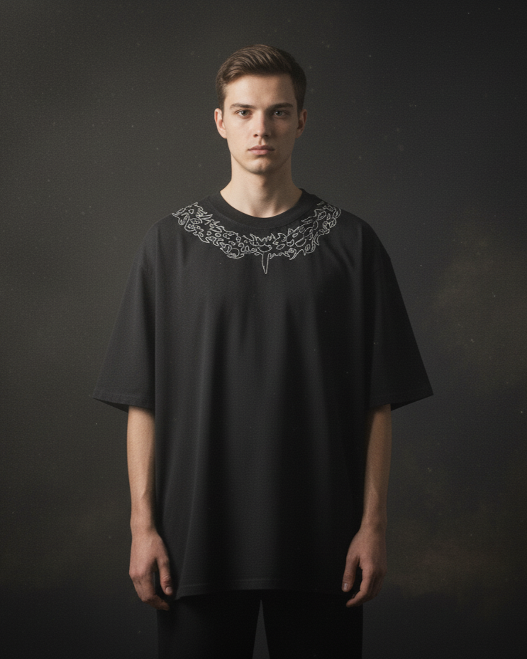 Man wearing a black t-shirt with intricate collar design against a dark background