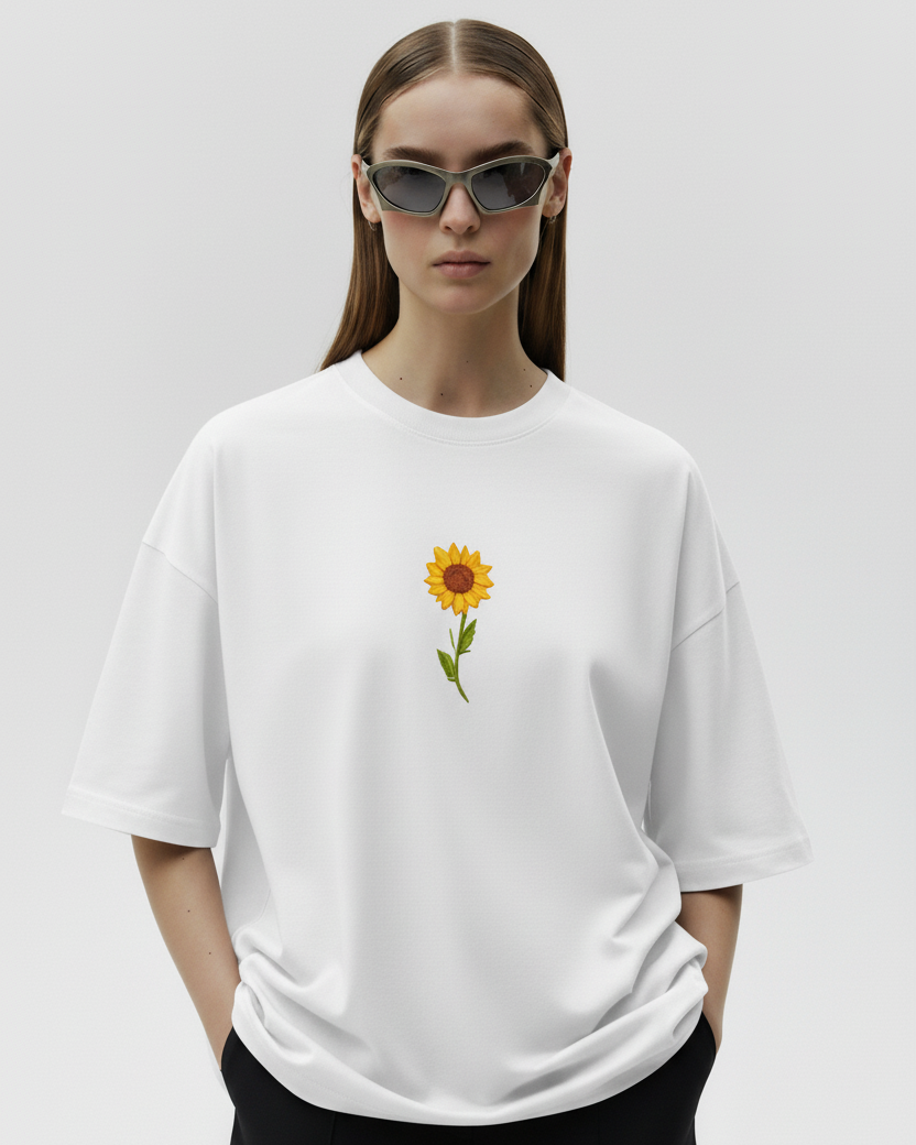 Person wearing a white t-shirt with a sunflower design embroidered on a plain background