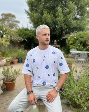 Man wearing a white t-shirt with floral patterns in an outdoor setting