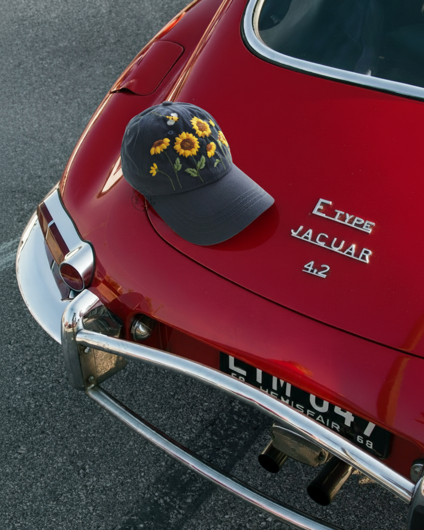 Black cap with floral design embroidered on a red Jaguar car