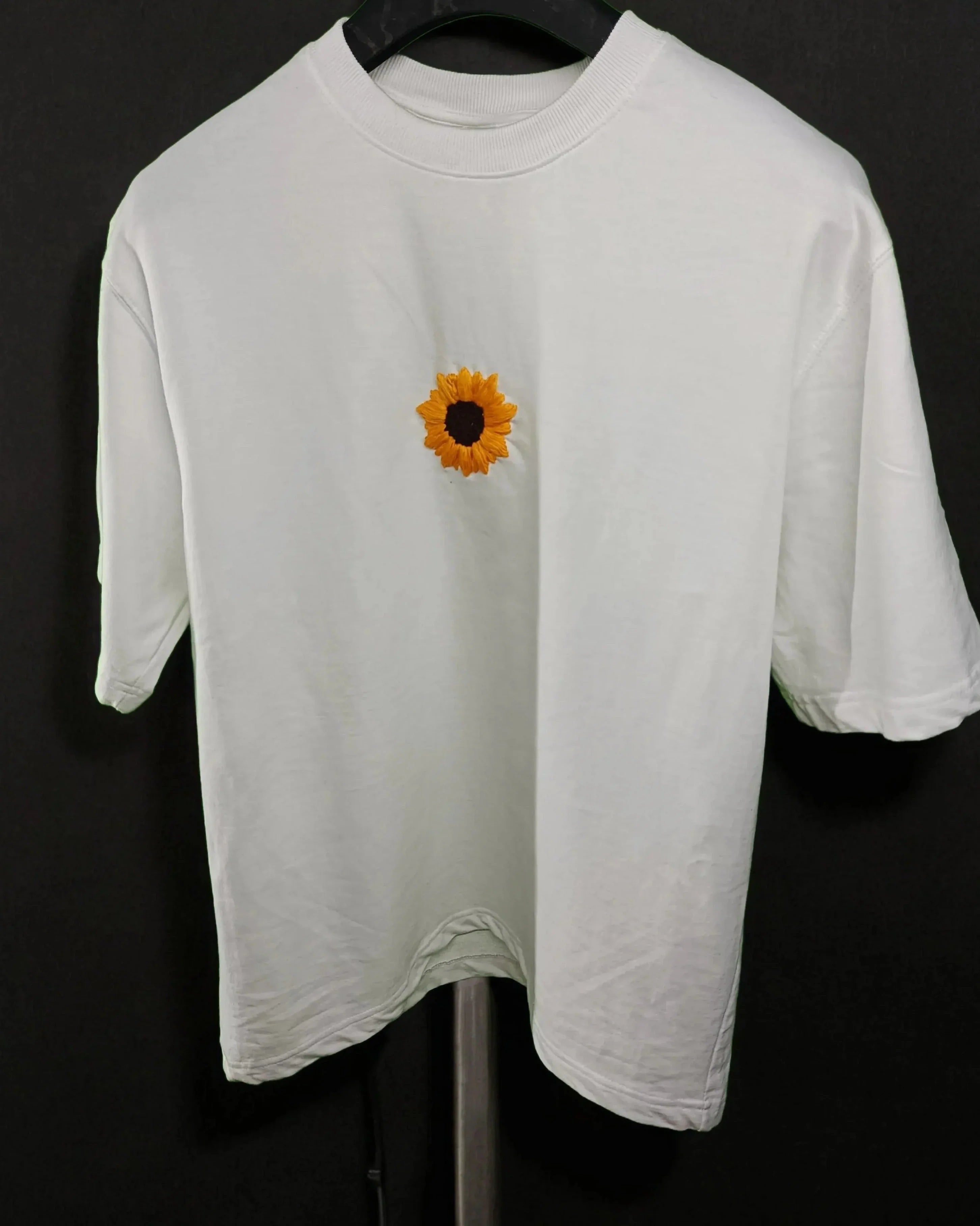 White t-shirt with a sunflower design on a black background