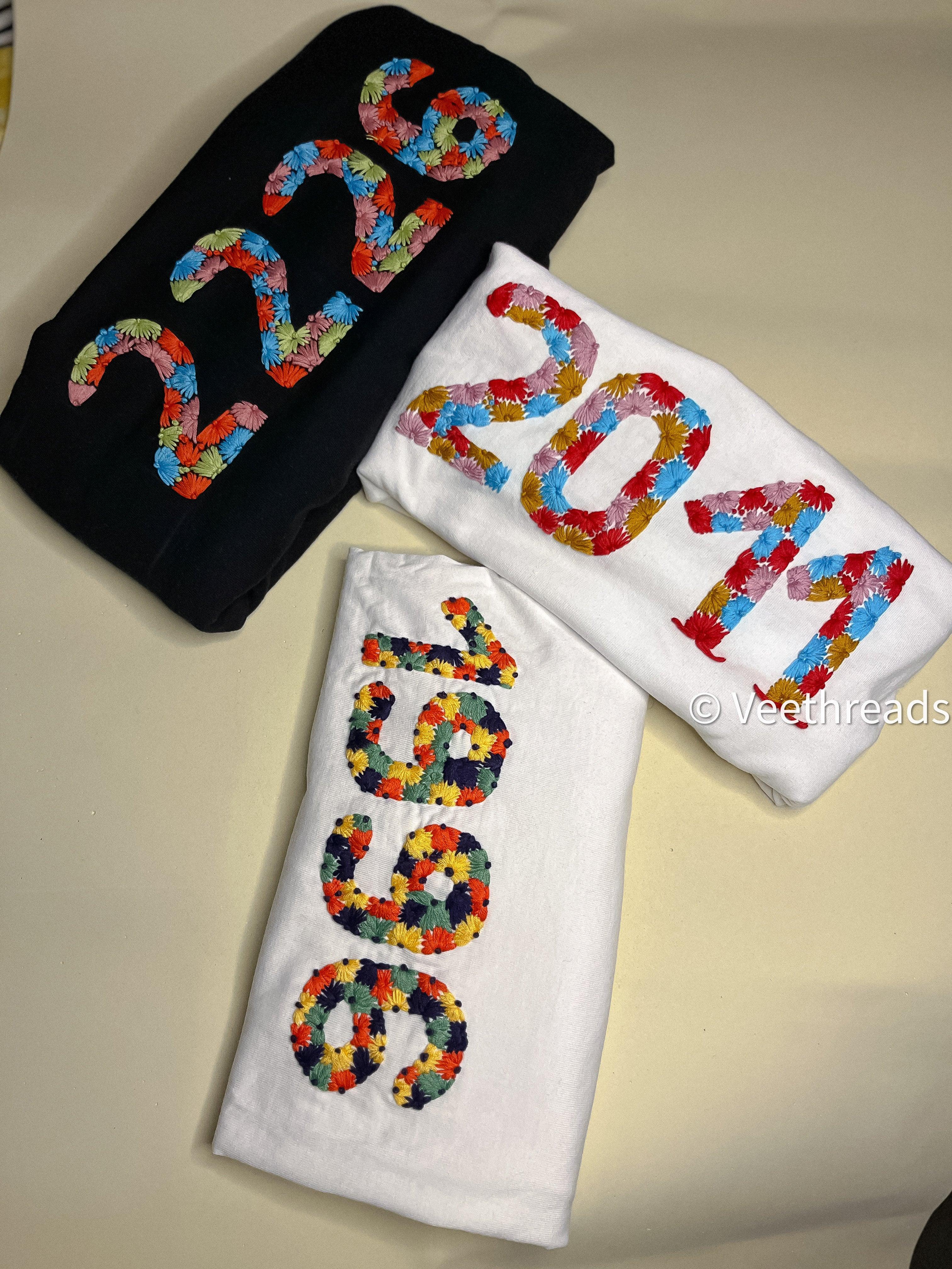 Minimalist flatlay of year customised tshirt, showing “2011” stitched on soft cotton near neckline.