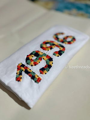 Flatlay of black custom t-shirt with “1996” hand-embroidered on chest in bold white thread.