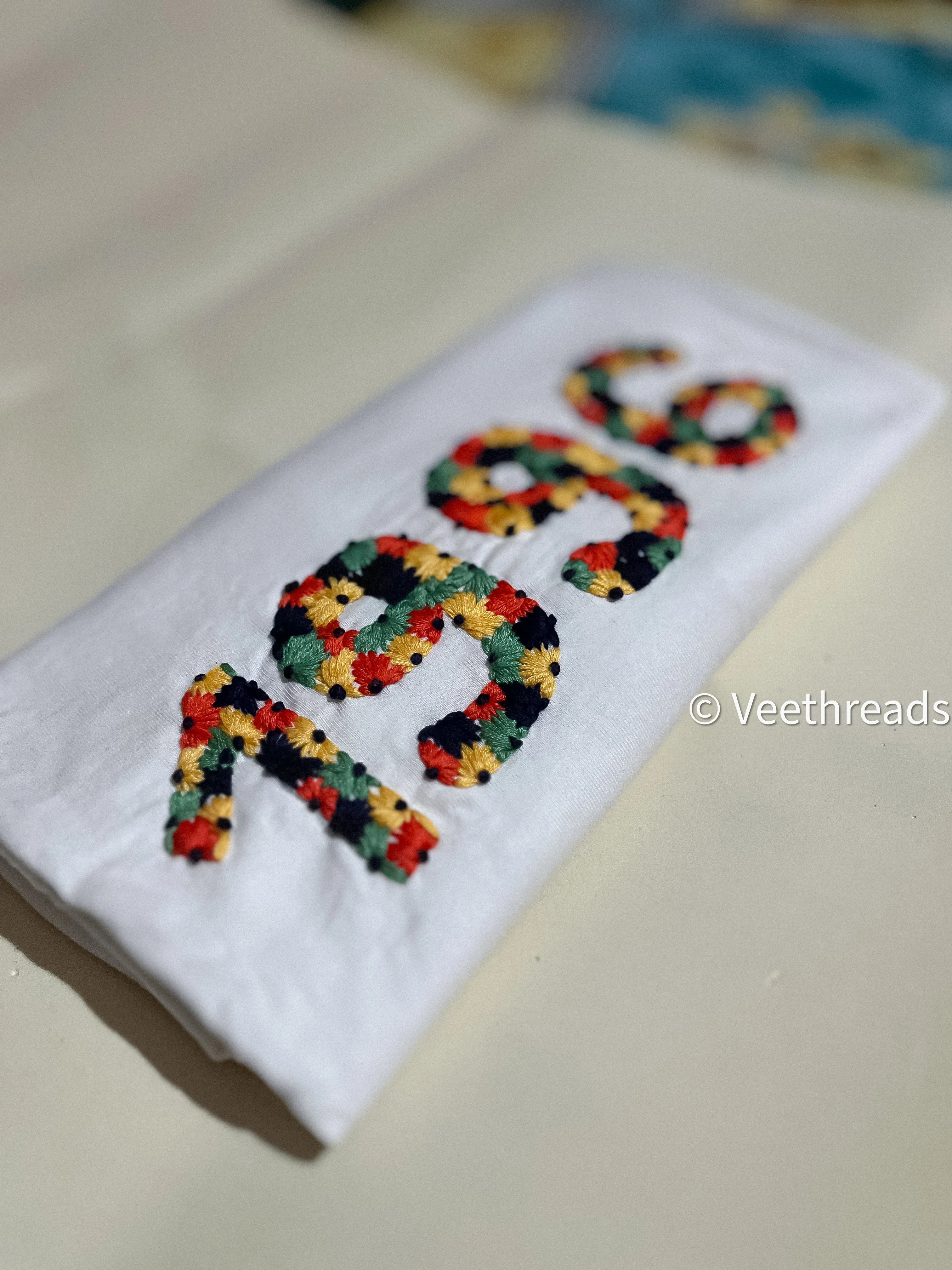 Flatlay of black custom t-shirt with “1996” hand-embroidered on chest in bold white thread.