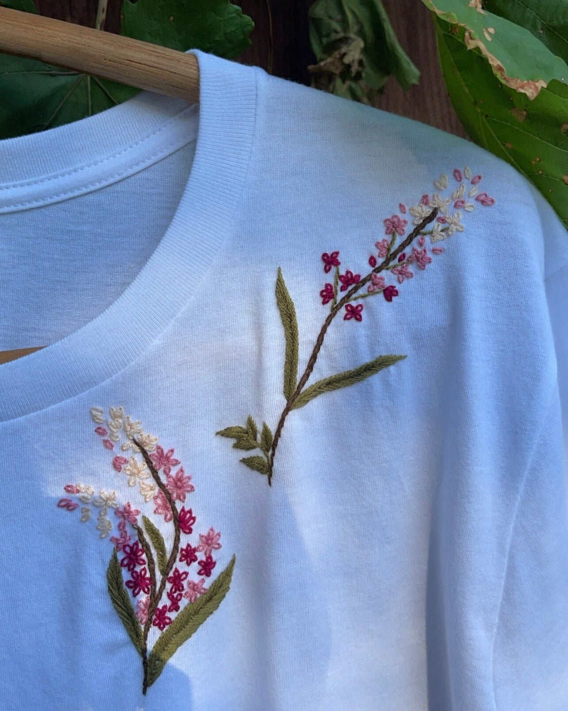 Hand embroidery designs for shirts floral — detail view of multicoloured floral embroidery showing real stitched petals on cotton tee