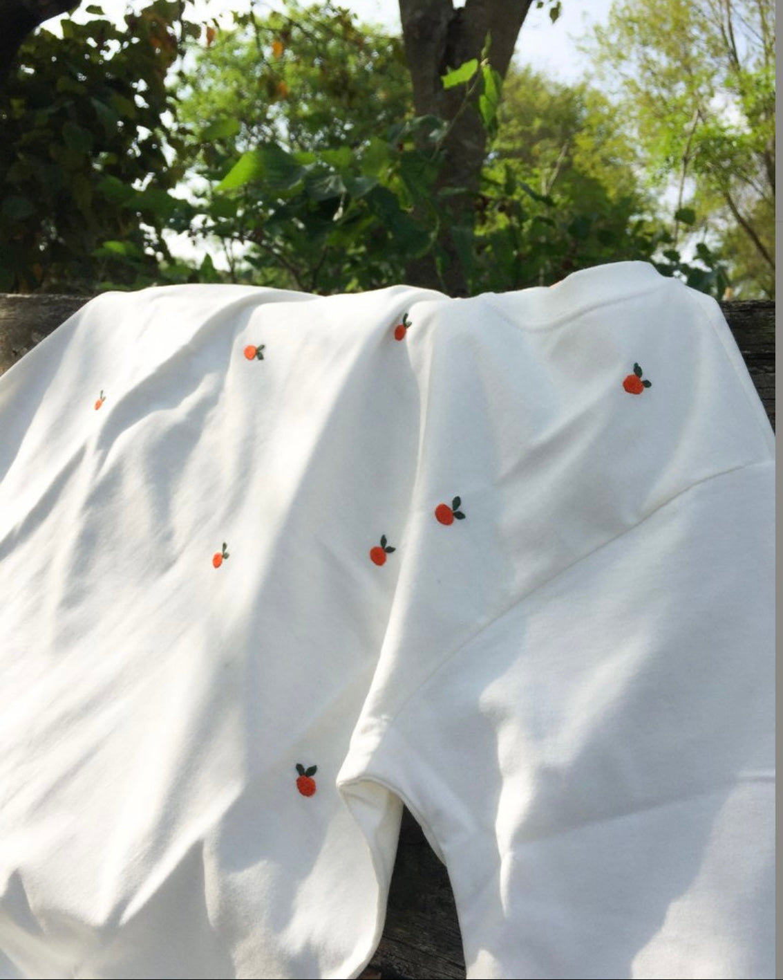 Food motif embroidered tee — close-up of red tomato embroidery on white cotton showing real raised thread texture