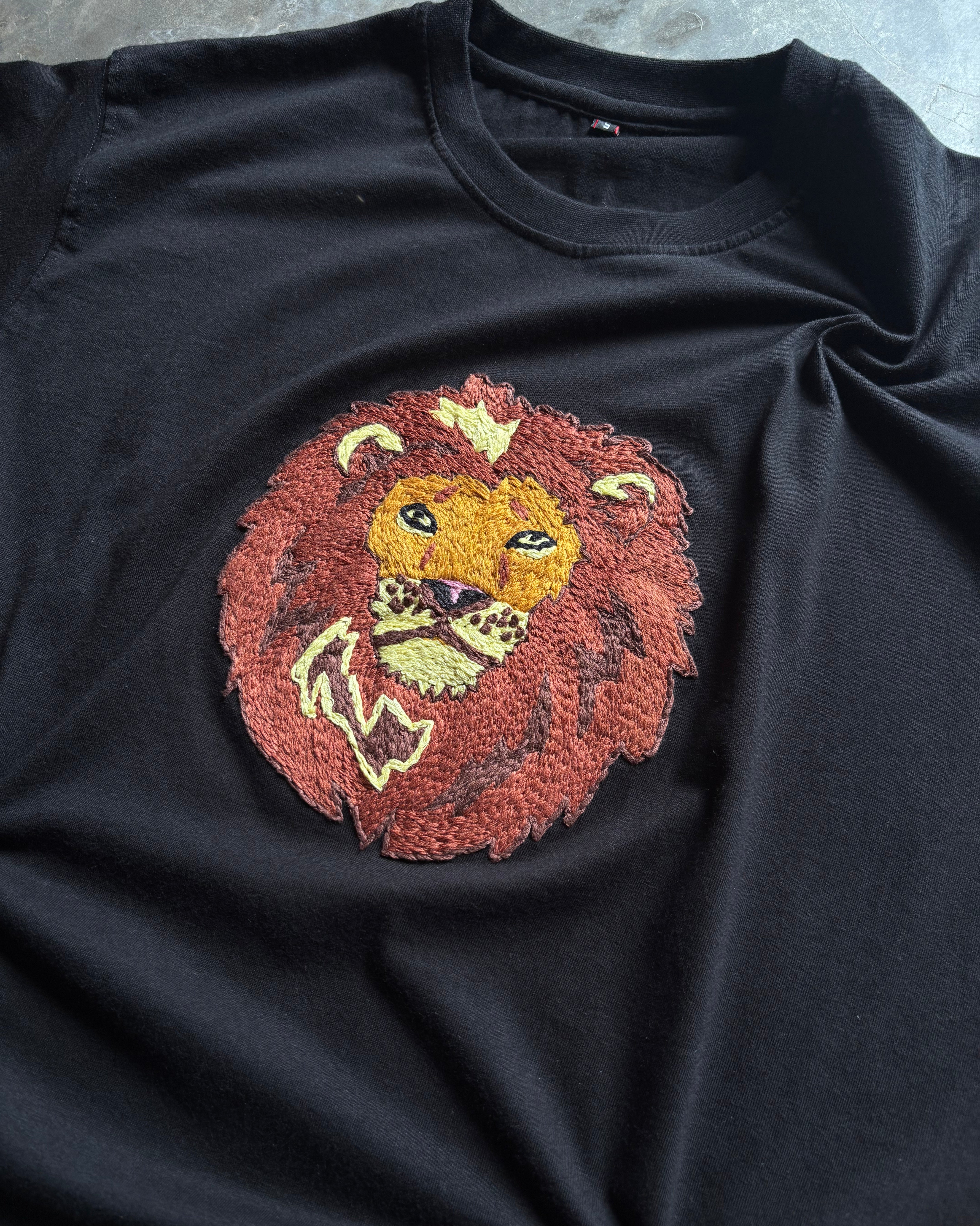 Black sleeveless shirt with a lion embroidered on a textured surface