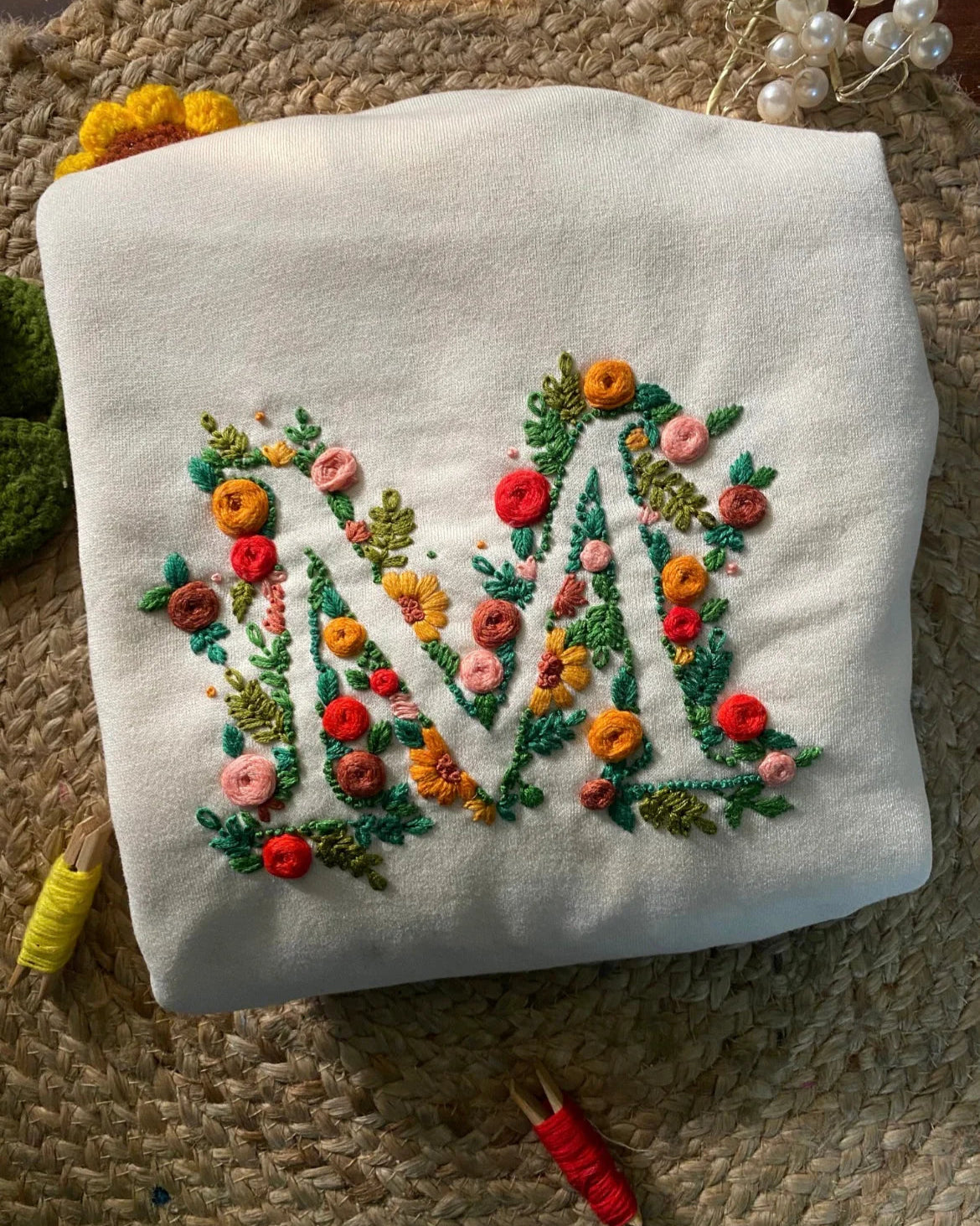 Macro shot of personalised initials stitched on a black sweatshirt, highlighting texture of fabric and embroidery.