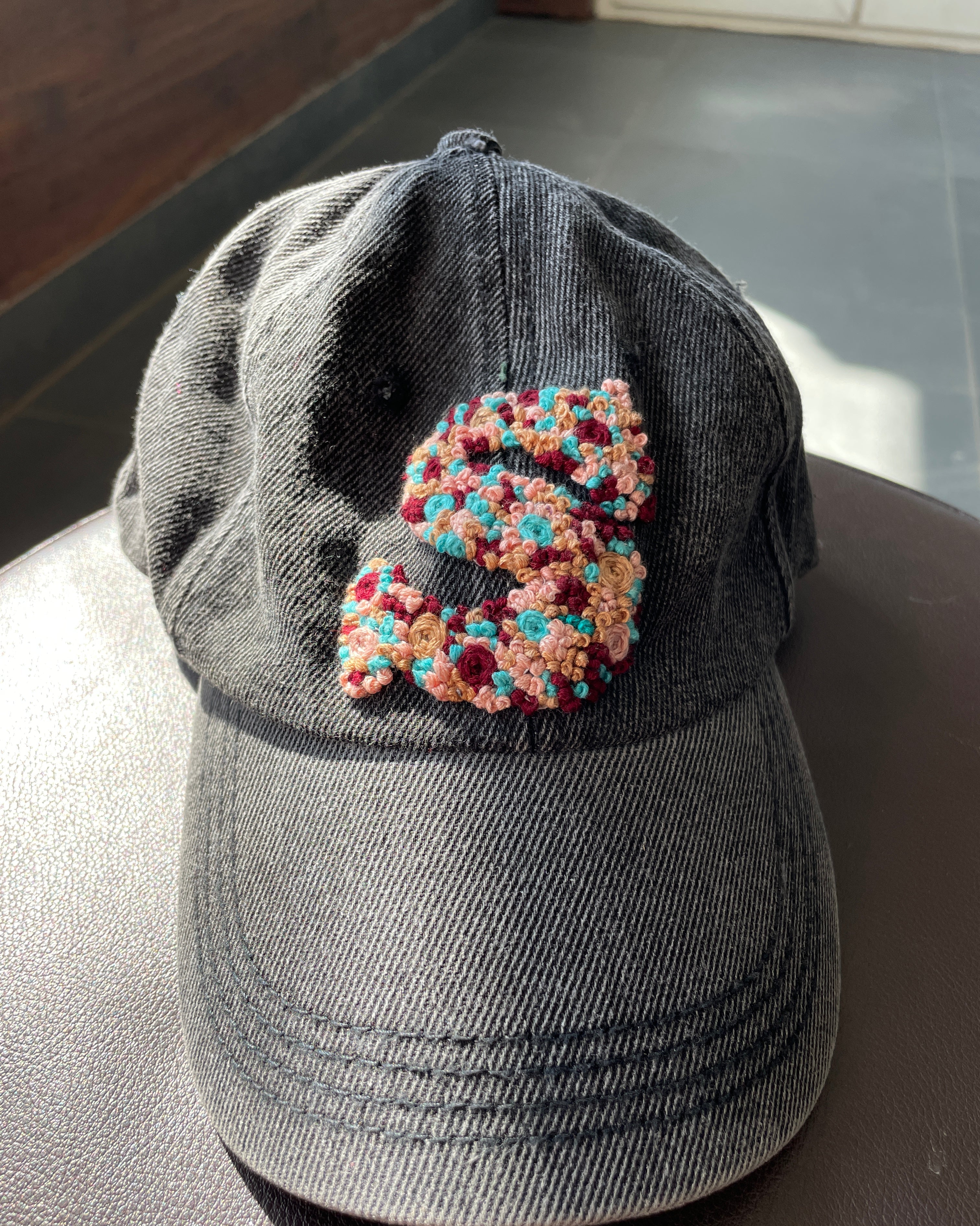 Custom Initials Hand-Embroidered Denim Caps lying on a seat