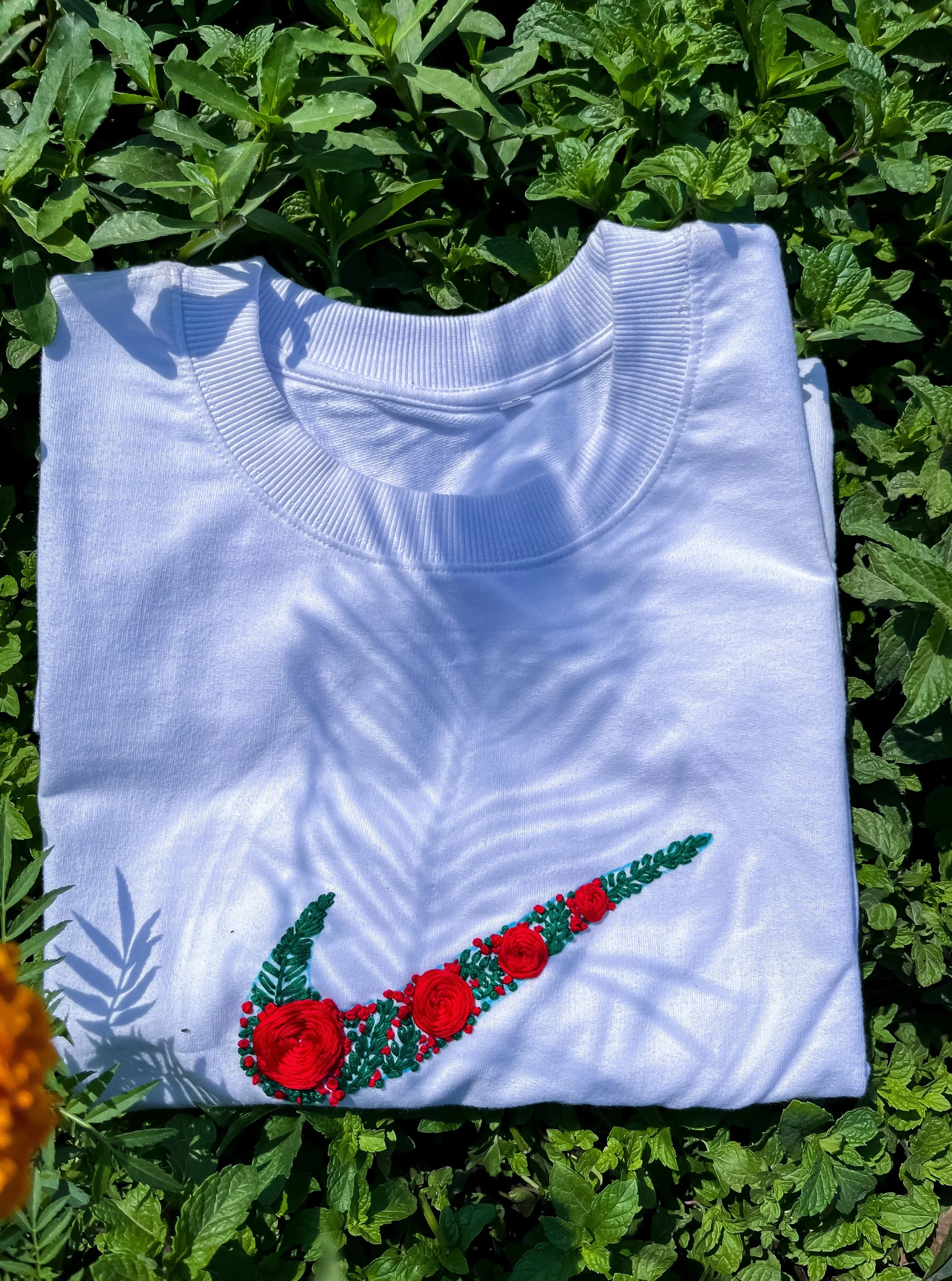 Close-up ofcolurfull embroidery swoosh logo on cotton Nike tee, highlighting thread texture and clean stitch.