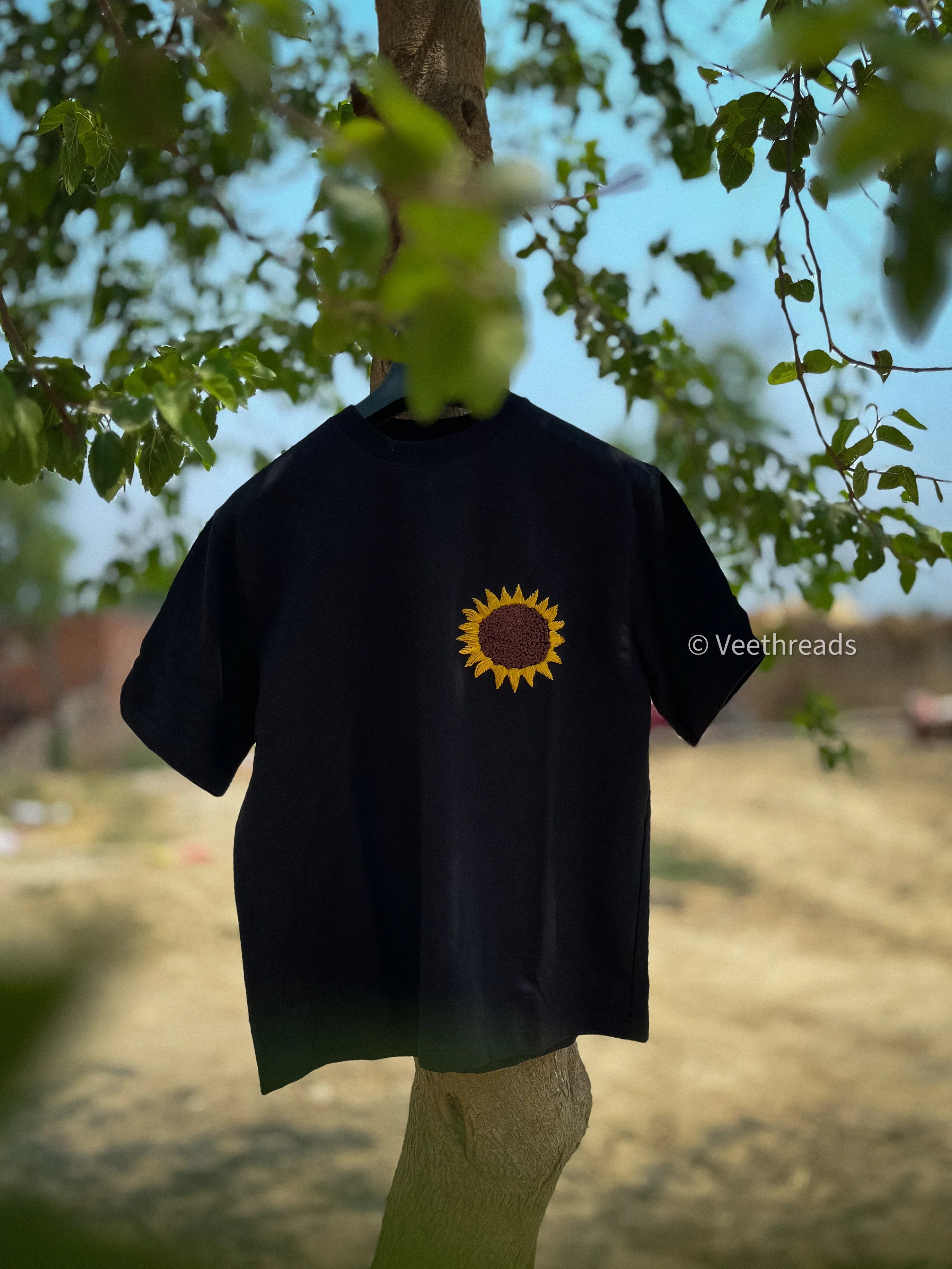 Black t-shirt with a sun design embroidered hanging outdoors