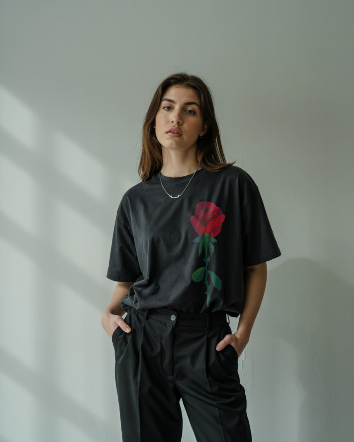 Unisex black rose embroidered t-shirt styled for streetwear with cargo pants and sneakers.