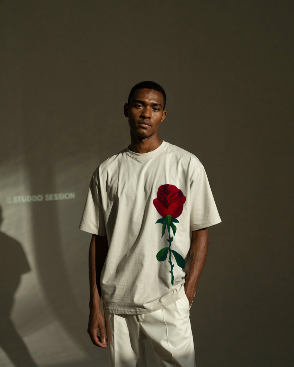 Model wearing black t-shirt with red rose embroidery on chest, paired with denim for a clean, casual look.