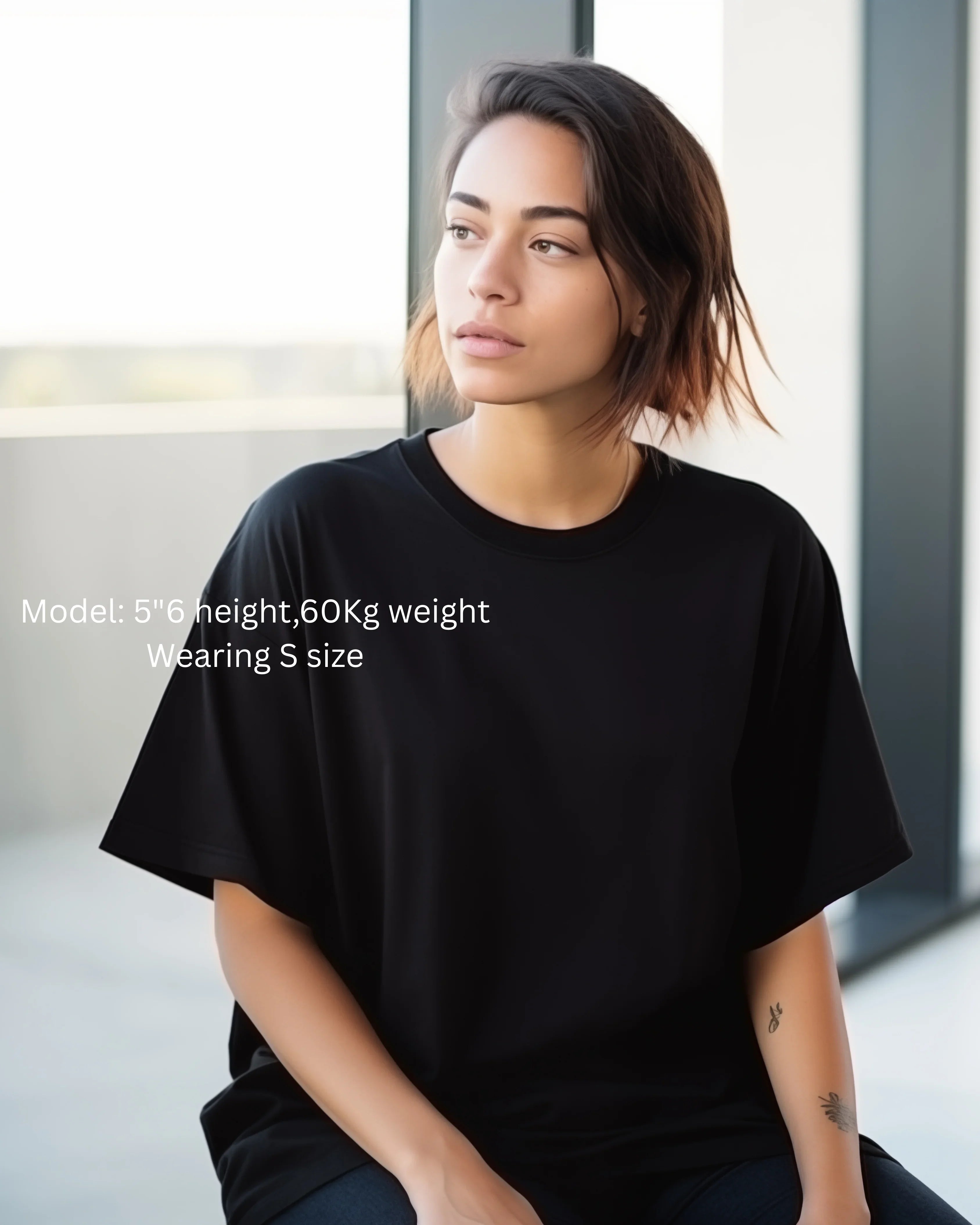 Person wearing a black t-shirt sitting indoors with neutral background
