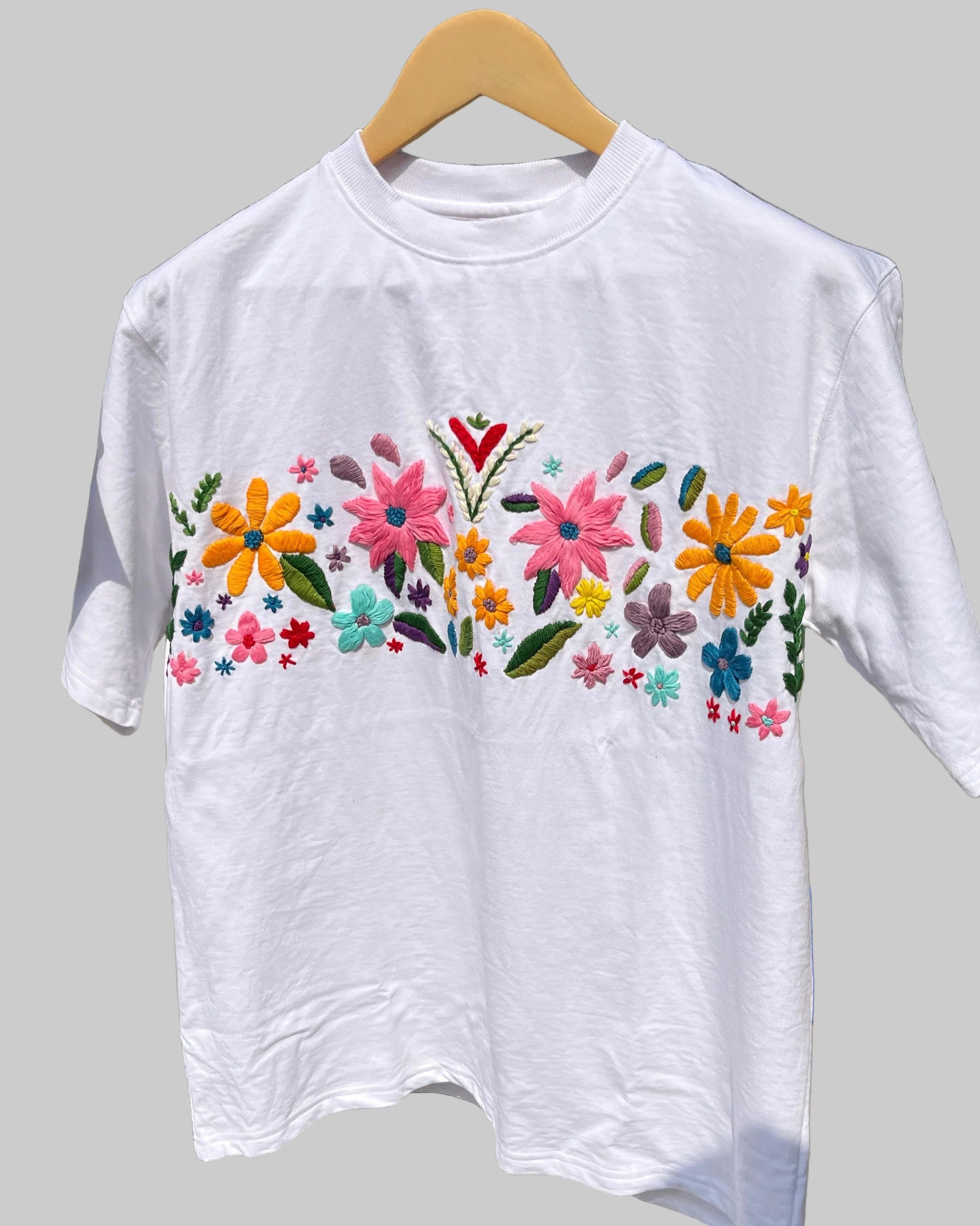 Flat lay of black cotton t-shirt with vibrant floral hand embroidery