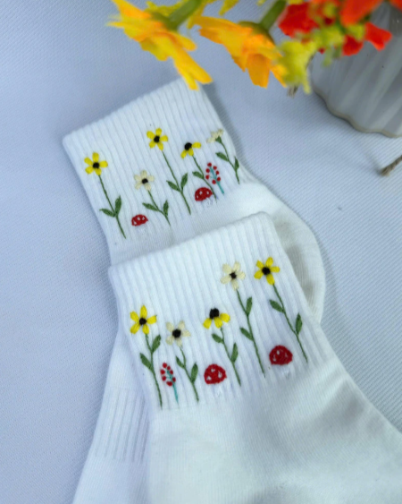 White socks with floral patterns embroidered on a light gray background