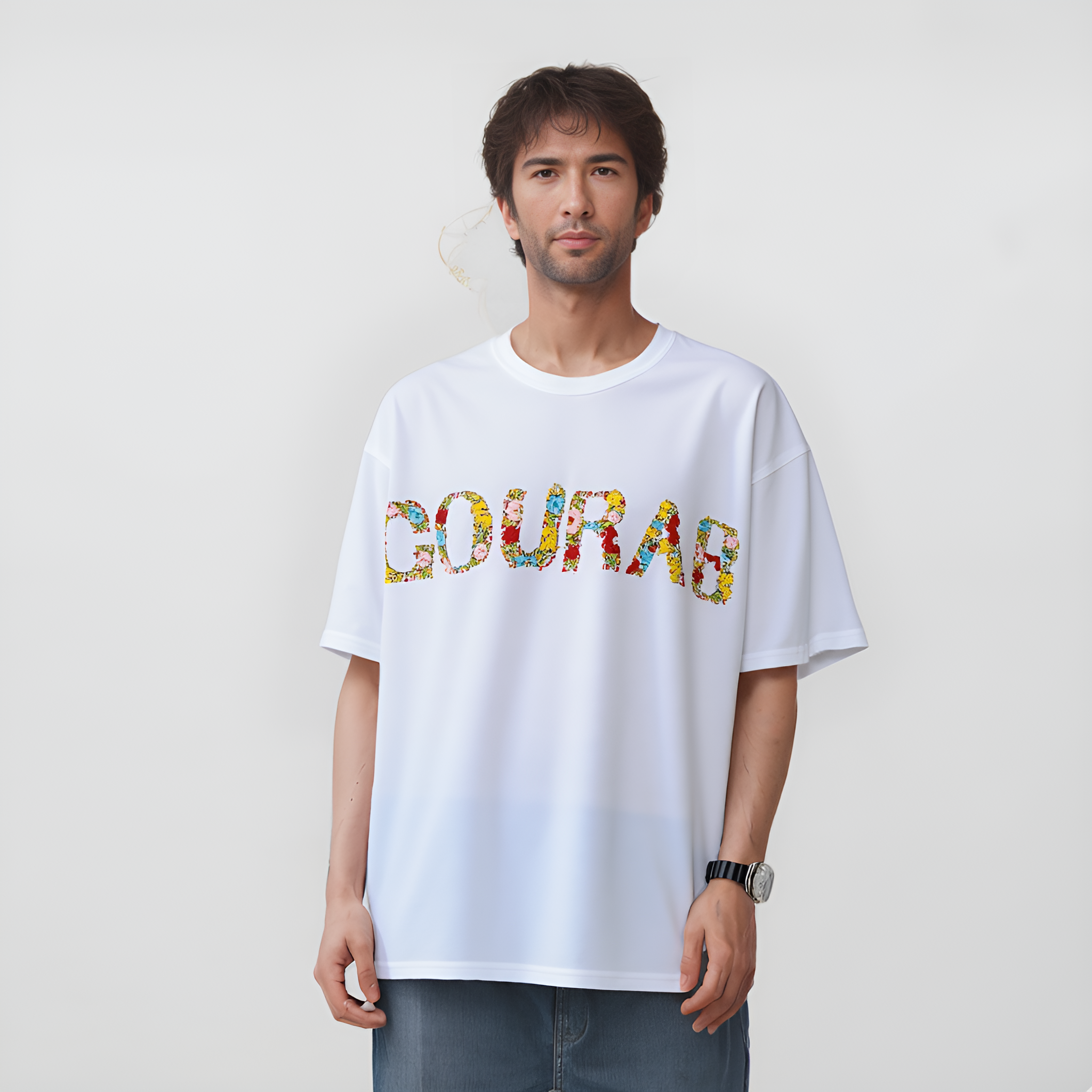 Person wearing a white t-shirt with personalized embroidery colorful text on a plain backgroud