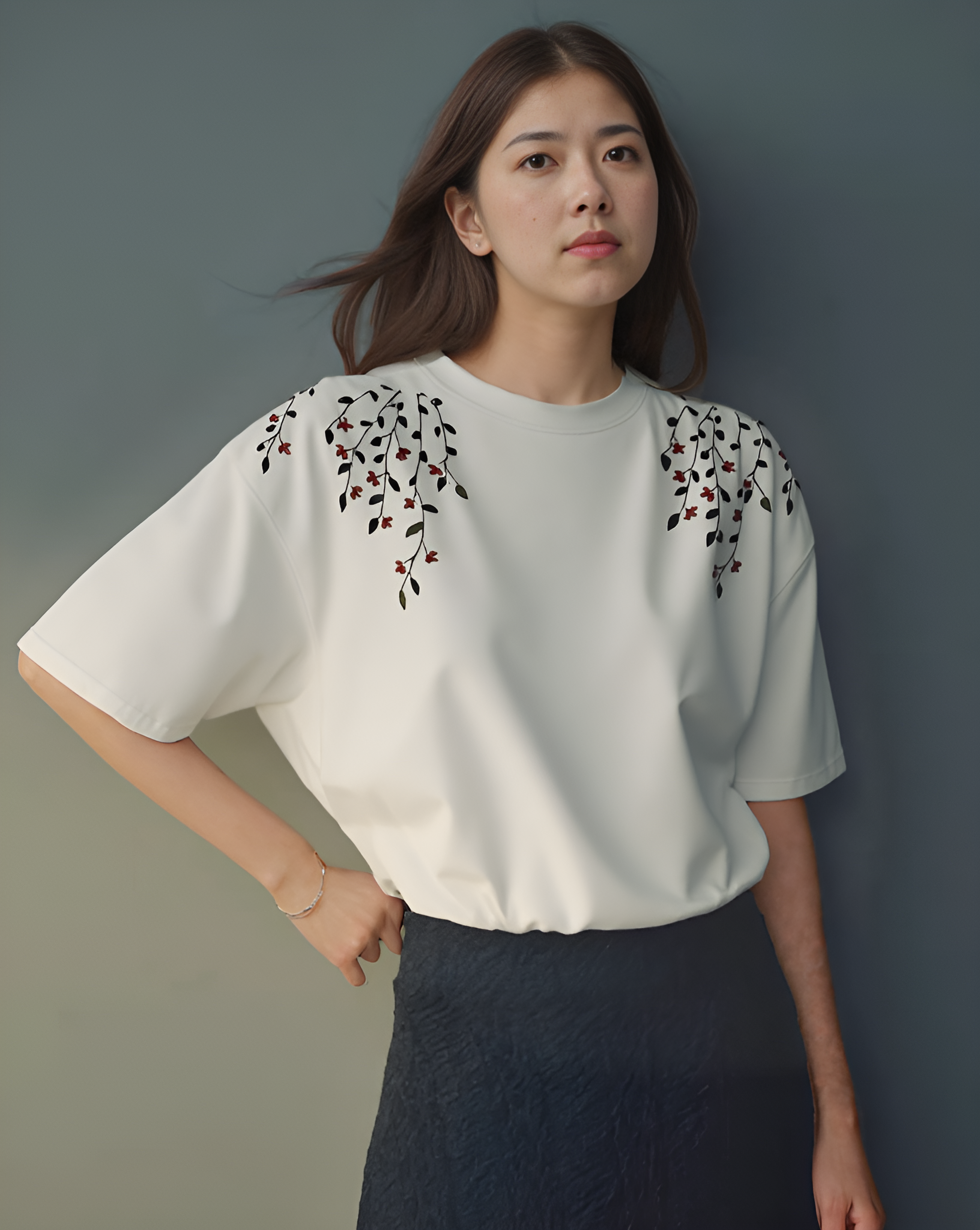 Model wearing a white cotton T-shirt featuring hand-embroidered floral vine design with colorful stitched flowers and leaves, styled in a relaxed fit.