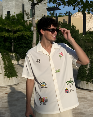 Man wearing a white shirt with colorful beach embroidery designs outdoors