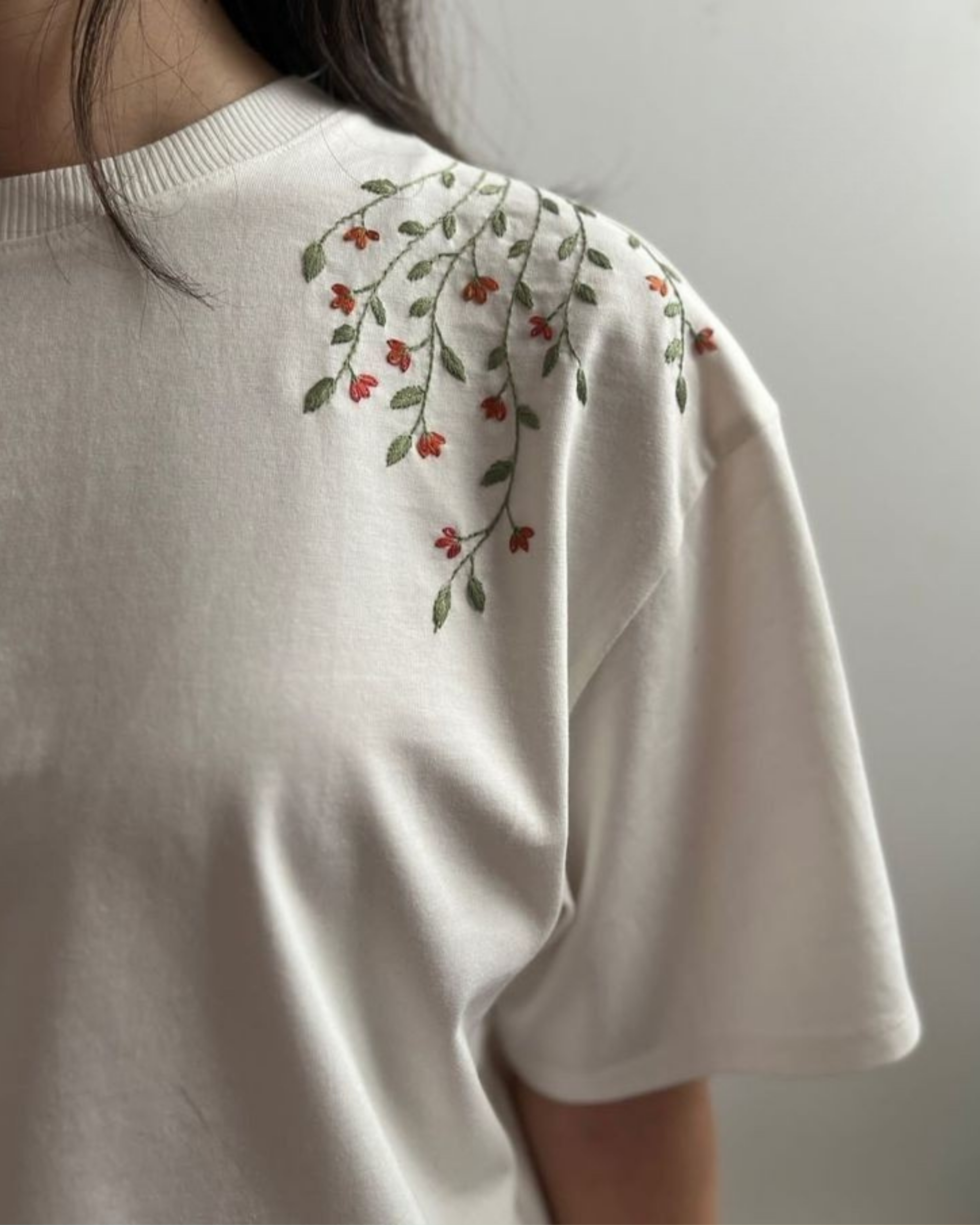 White t-shirt with floral embroidery on a plain background