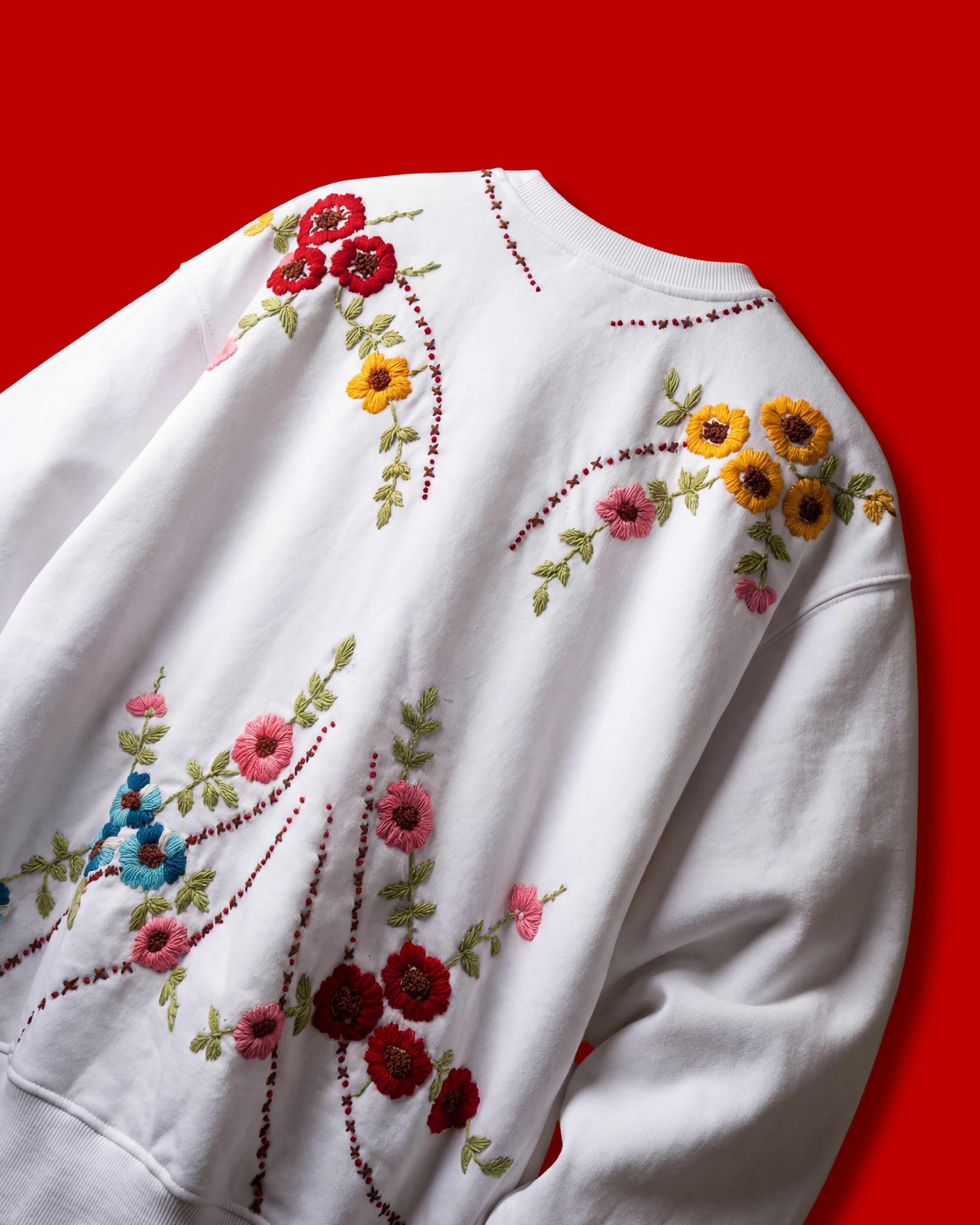 White hoodies with colorful floral embroidery on a red background