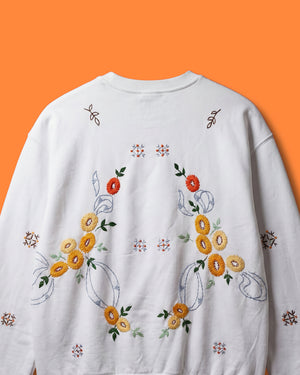 White sweatshirt with floral embroidery on an orange background