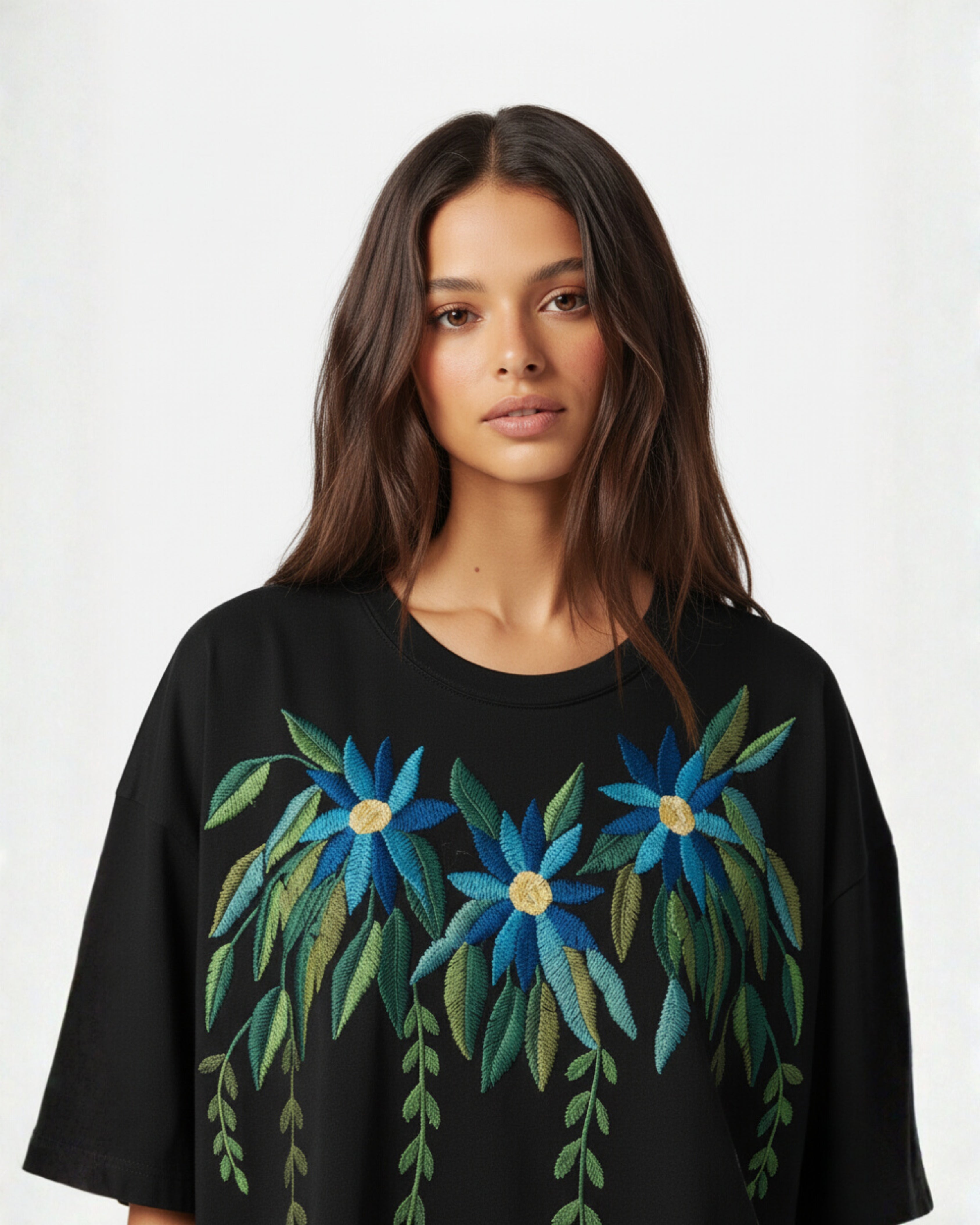 Woman wearing a black top with blue floral embroidery on a white background
