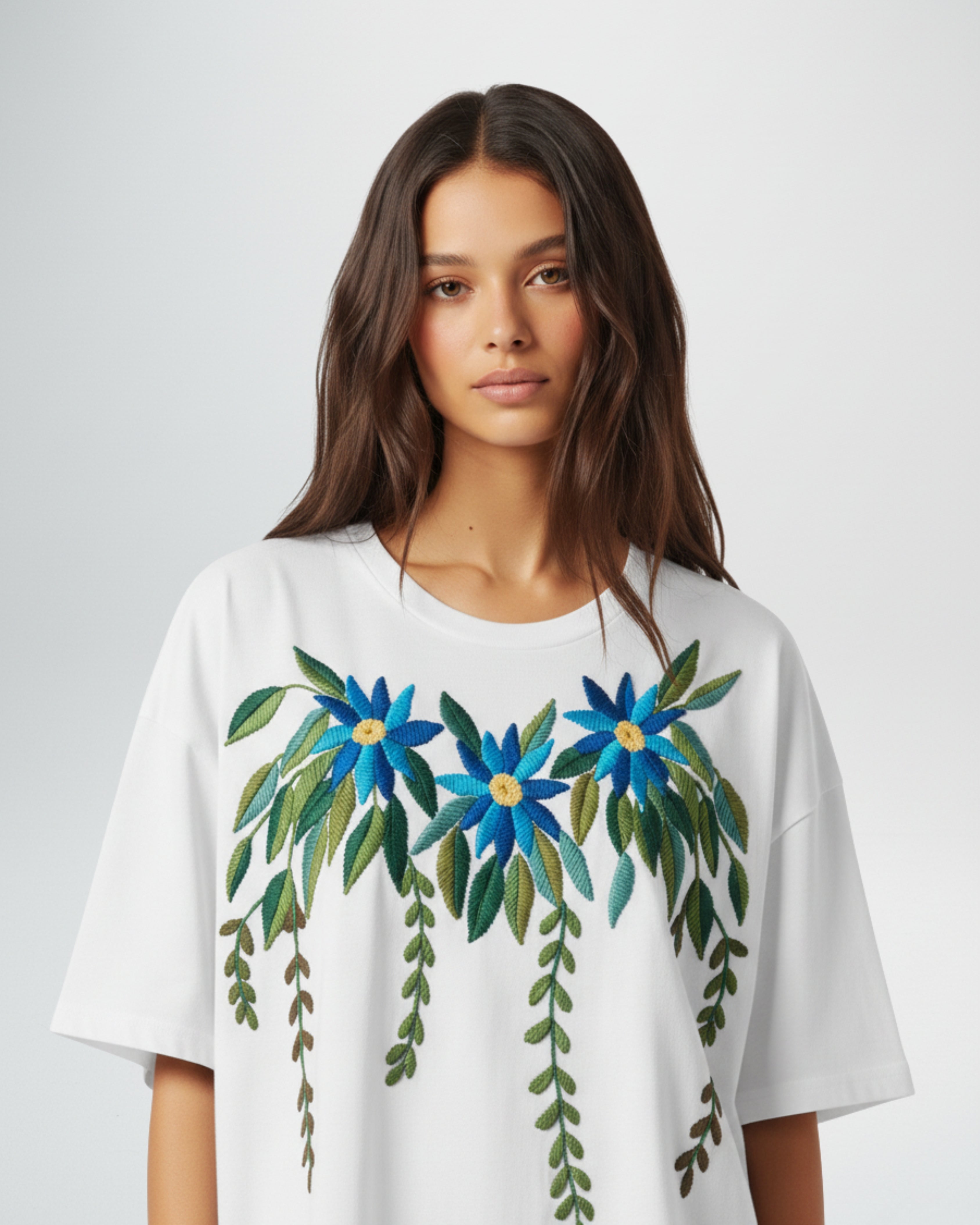 Woman wearing a white t-shirt with blue floral designs on a plain background