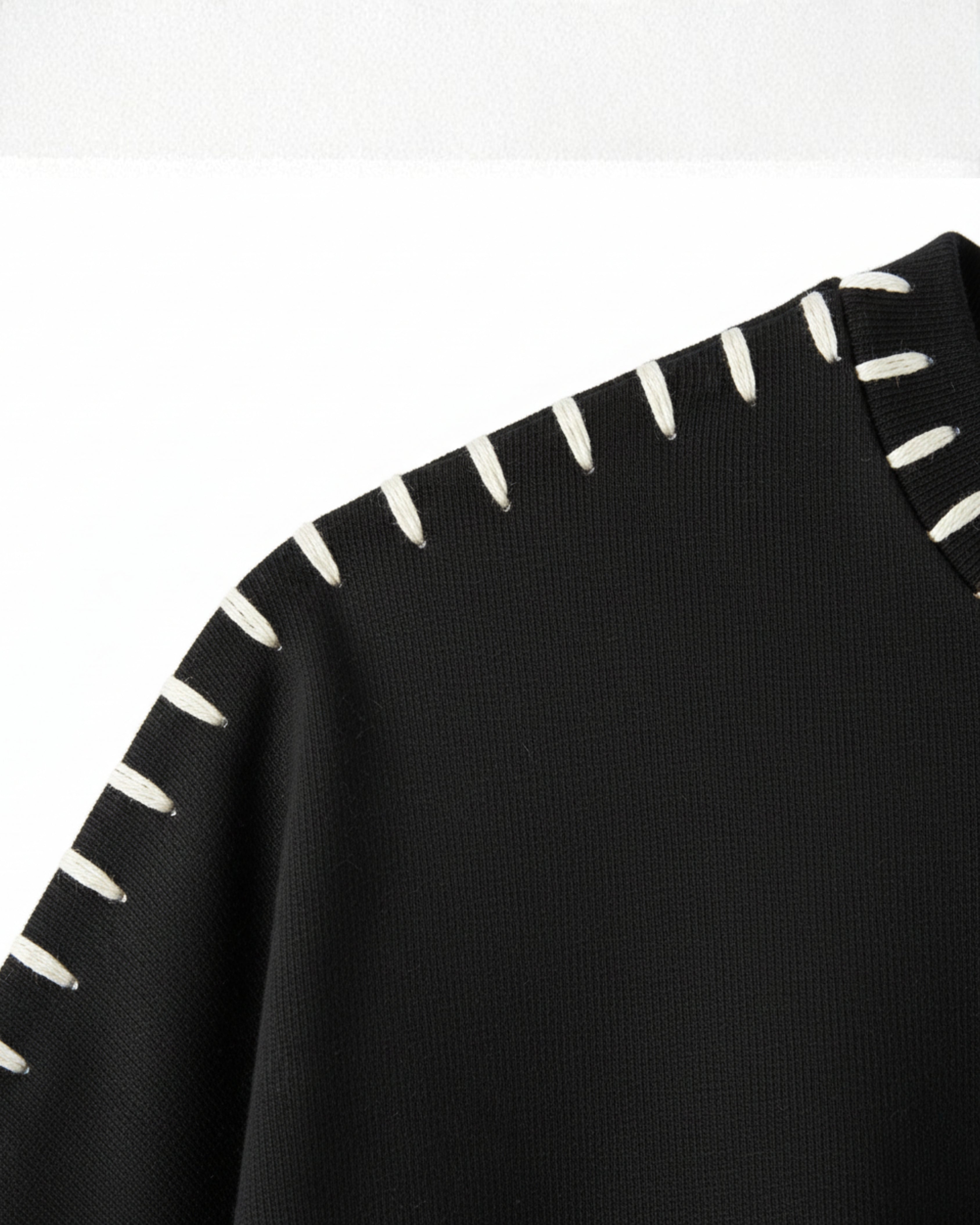 Close-up of black fabric with white lines embroidered on a white background