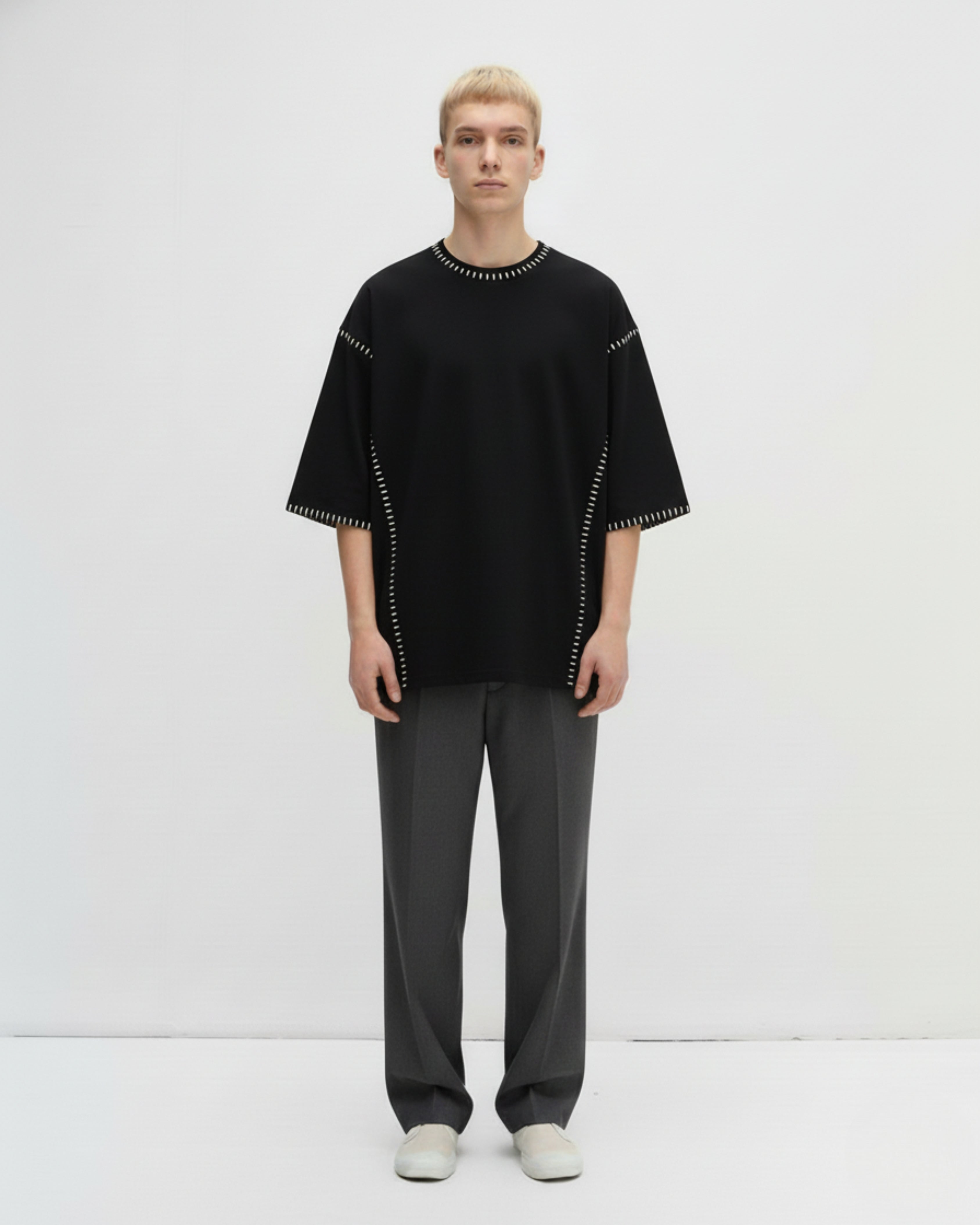 Person wearing a black hand embroidered tshirt outfit with white accents on a white background