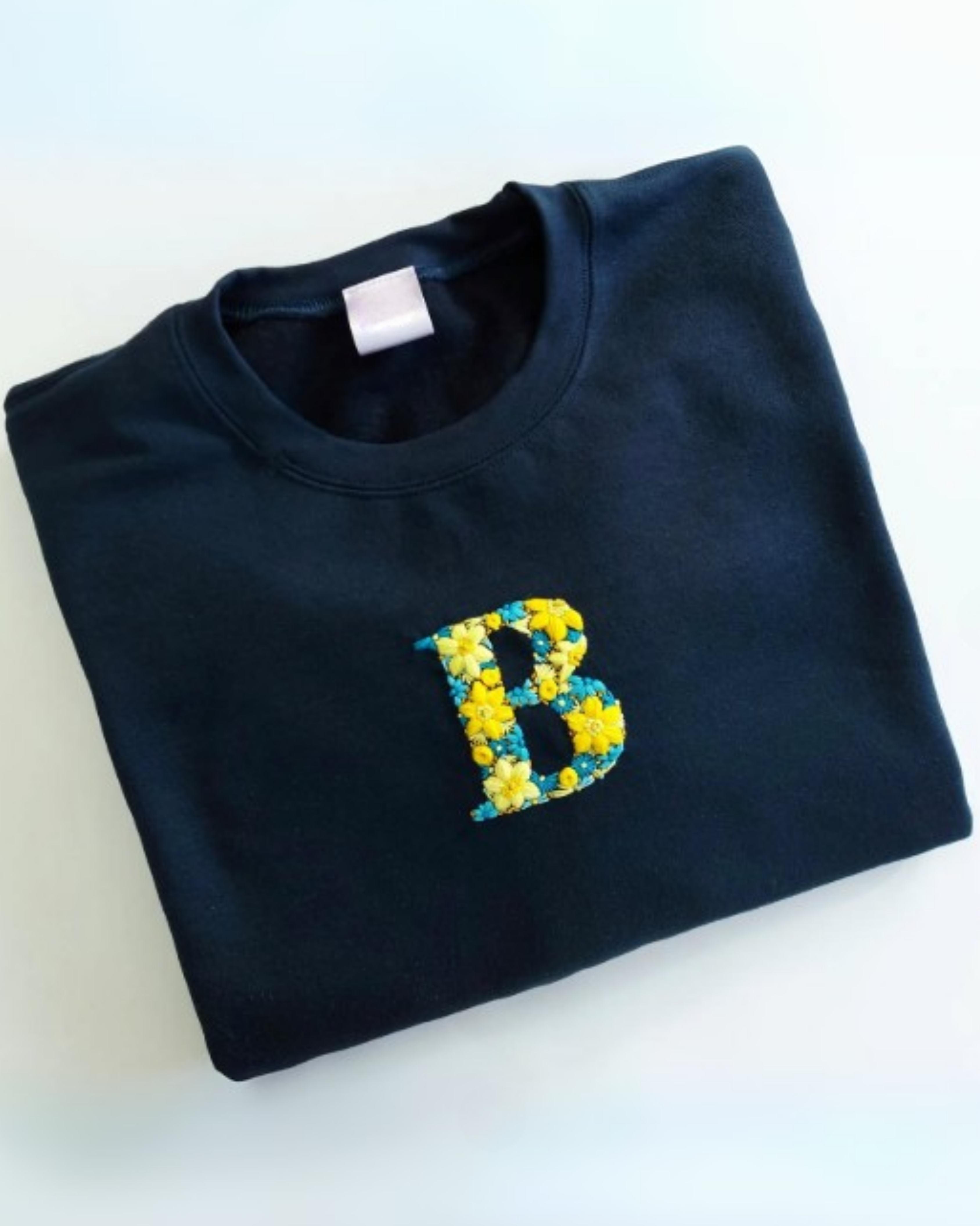Flat lay of black oversized cotton t-shirt with custom hand-embroidered name initials
