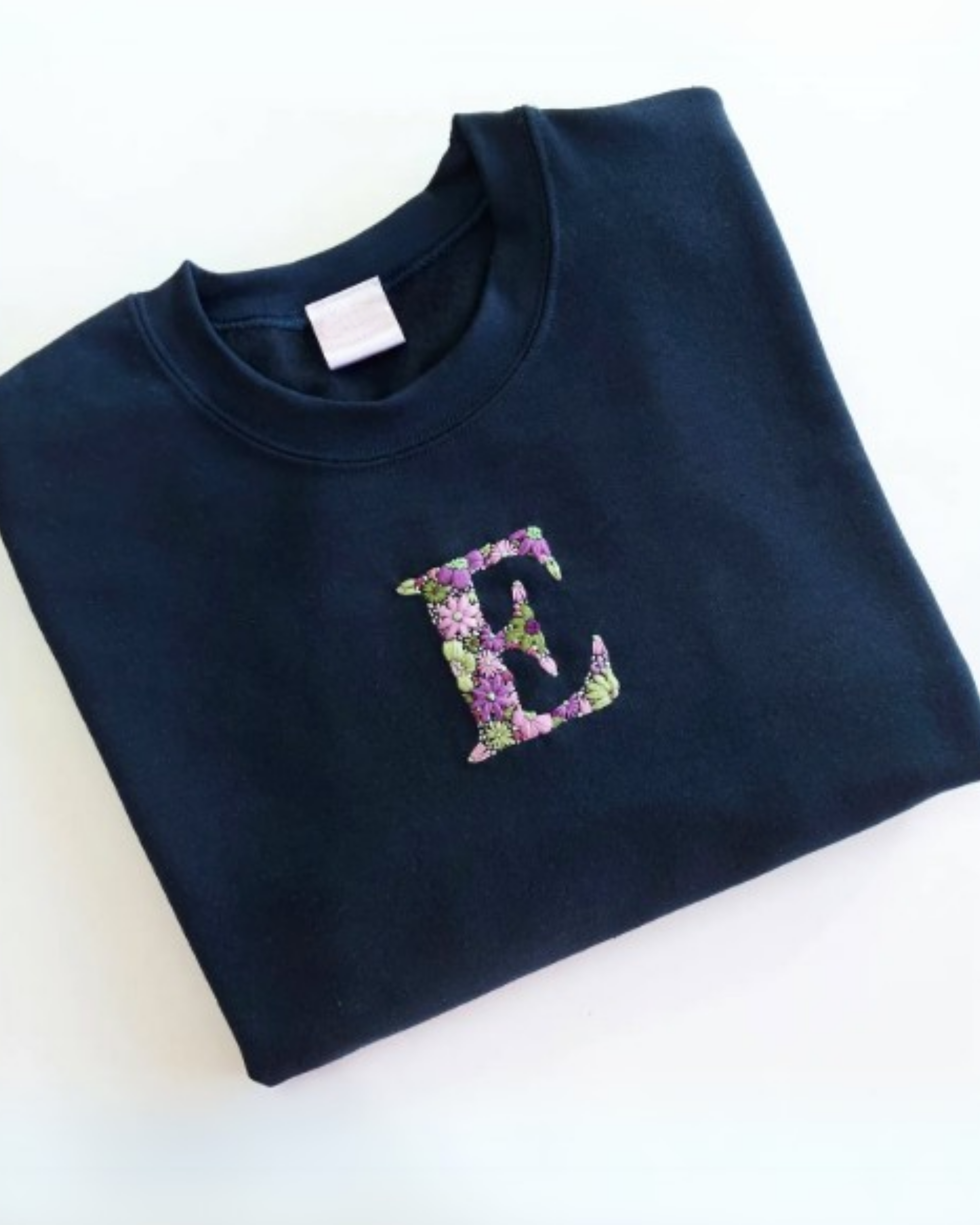 Personalized hand-embroidered initials t-shirt in flat lay on neutral background