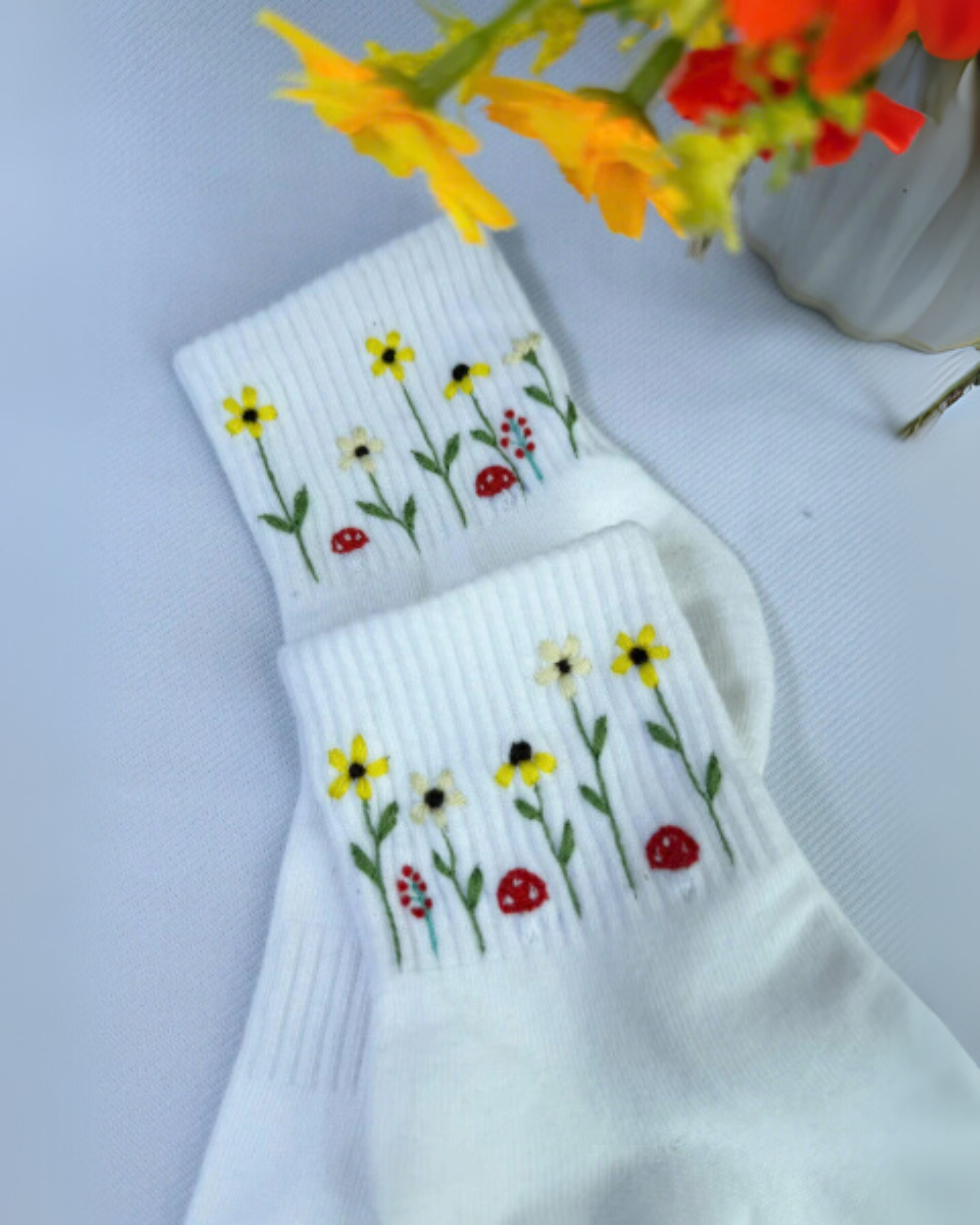 White socks with floral embroidered designs on a light gray background
