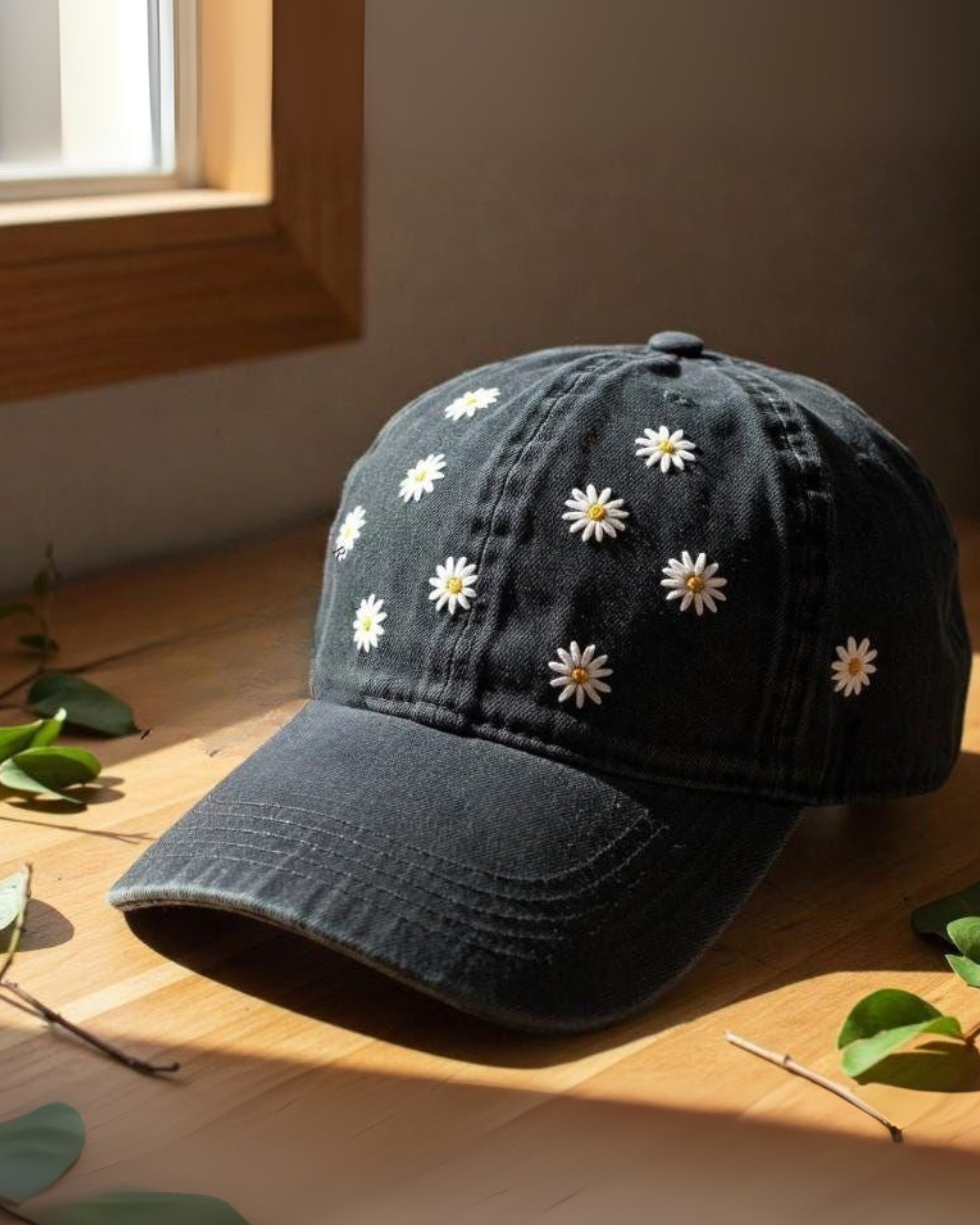 Black baseball cap with white daisy flowers embroidered placing on a wooden surface
