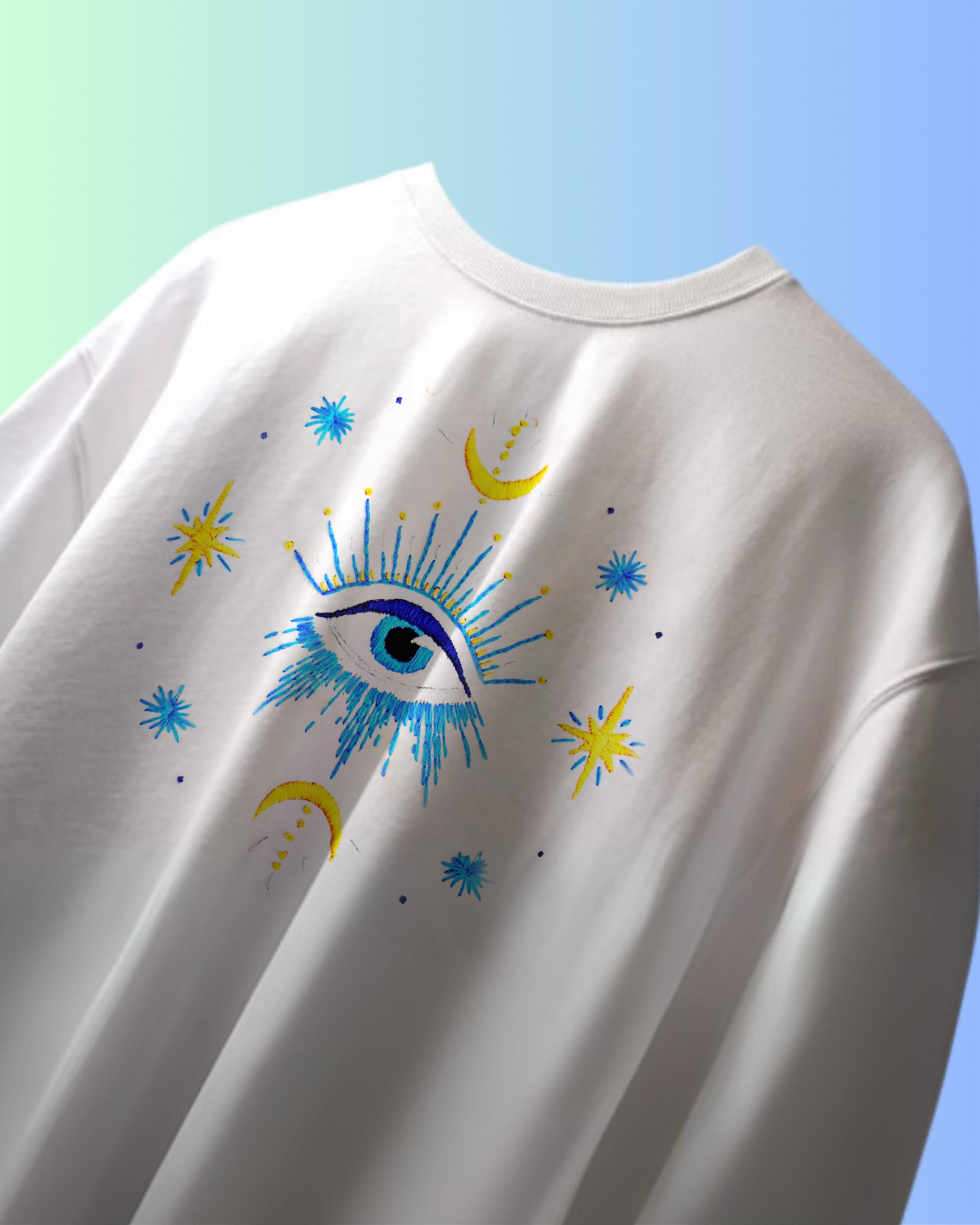 Flat lay of evil eye t-shirt with hand-embroidered design on black cotton