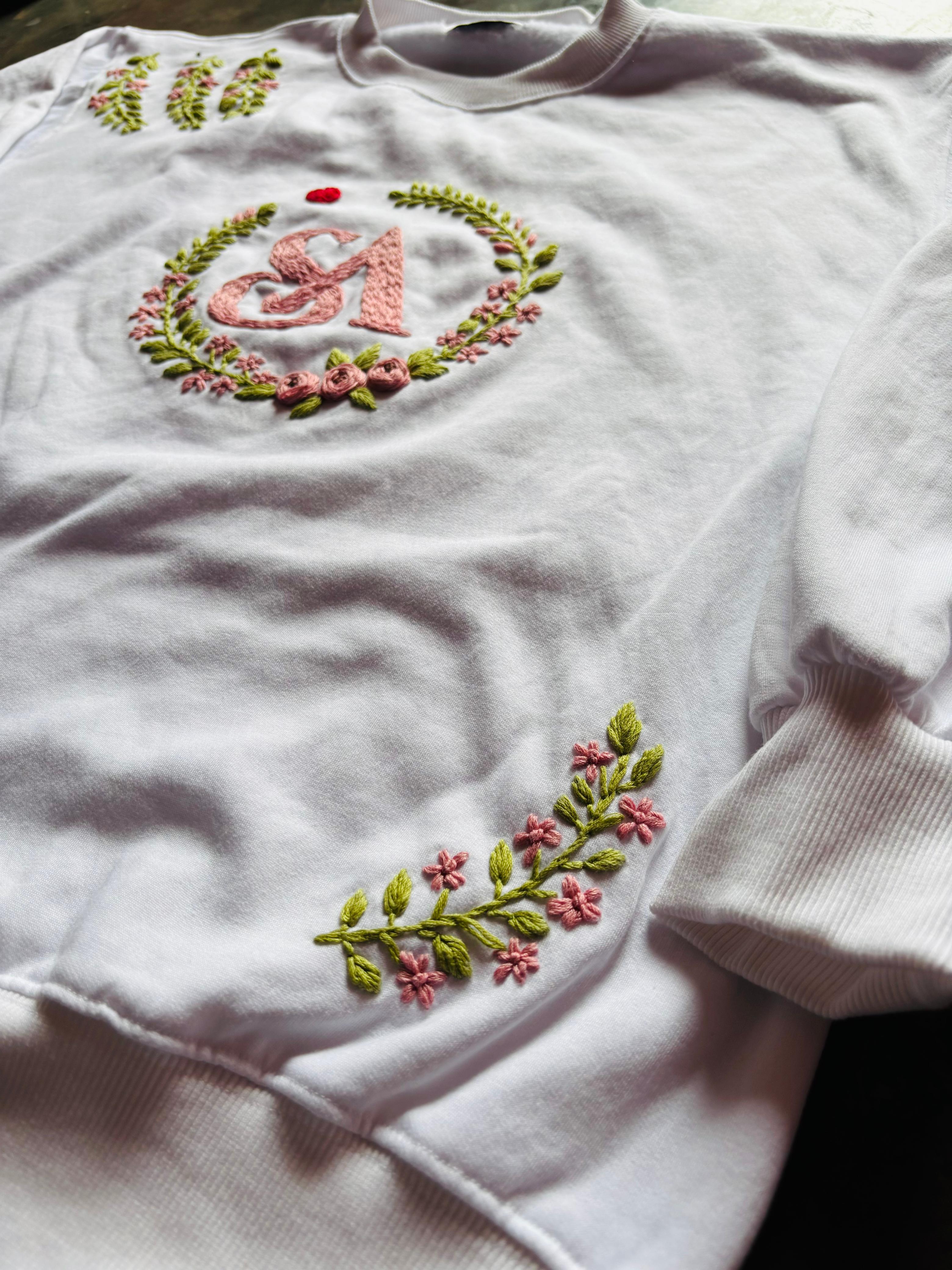 White sweatshirt with floral embroidery design on a plain background