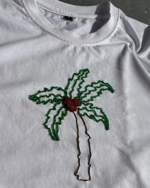 White t-shirt with a palm tree design bead embroidered on a dark background