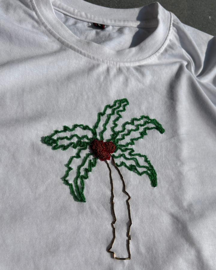 White t-shirt with a palm tree design bead embroidered on a dark background