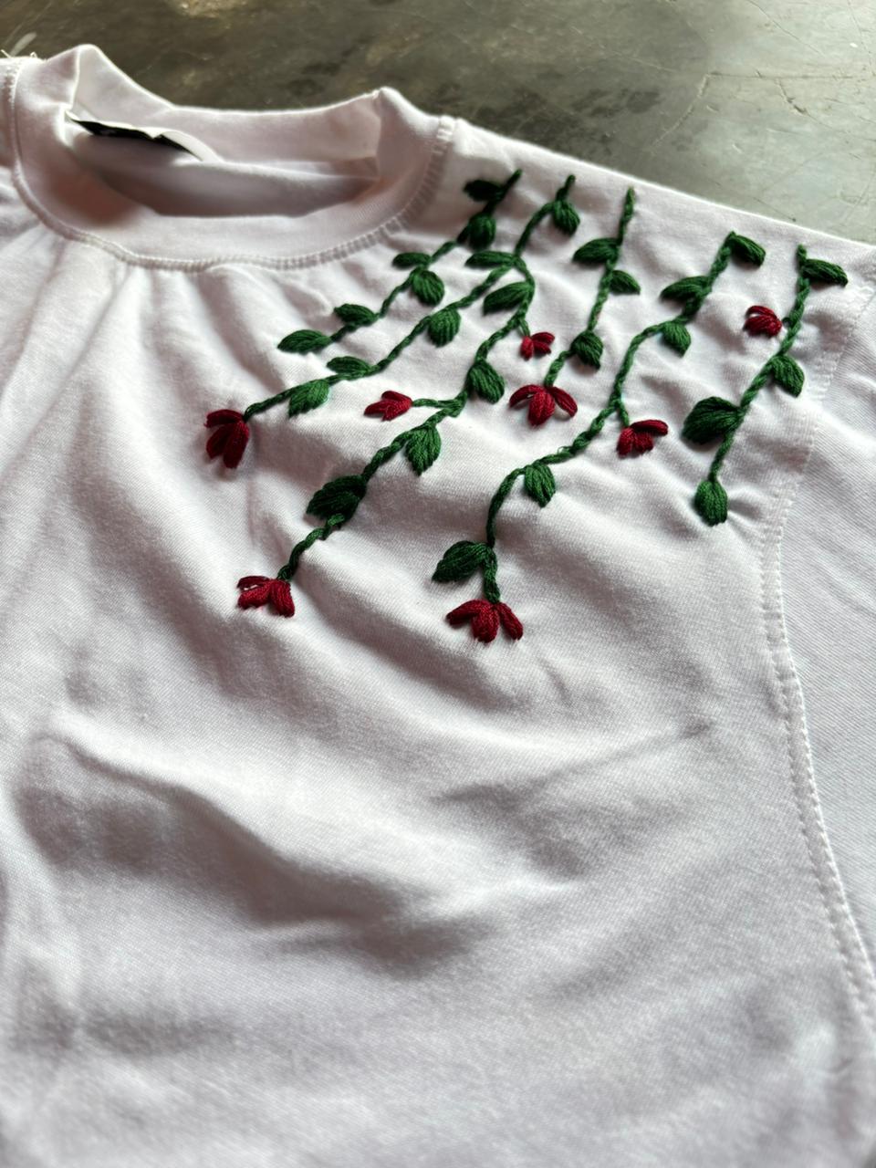 White shirt with red floral embroidery on a concrete surface