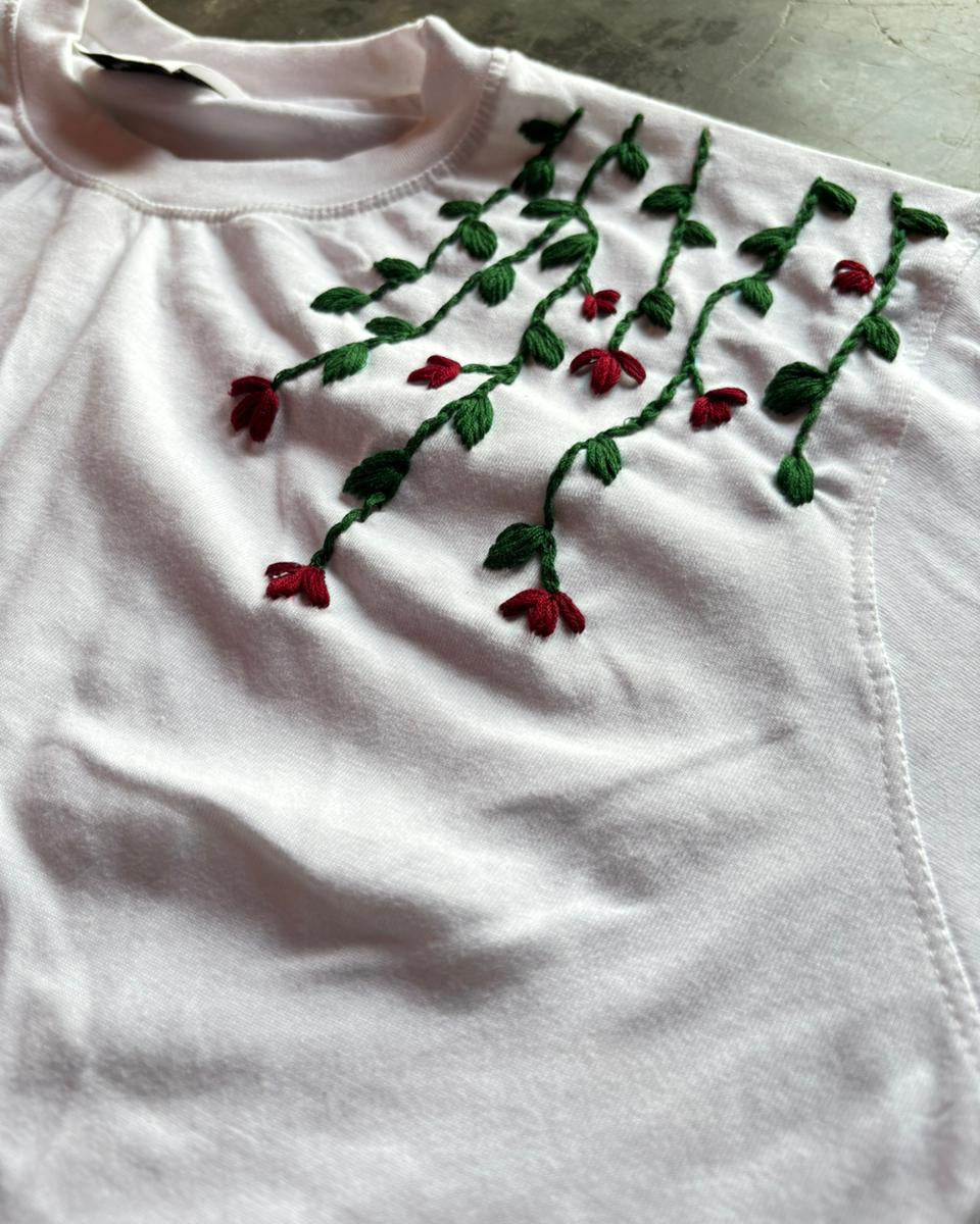 White shirt with red floral embroidery on a concrete surface