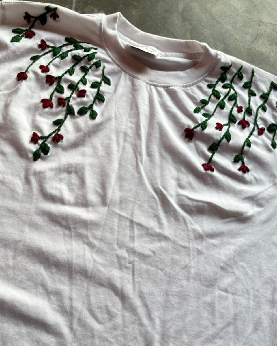 White t-shirt with floral embroidery on a textured surface