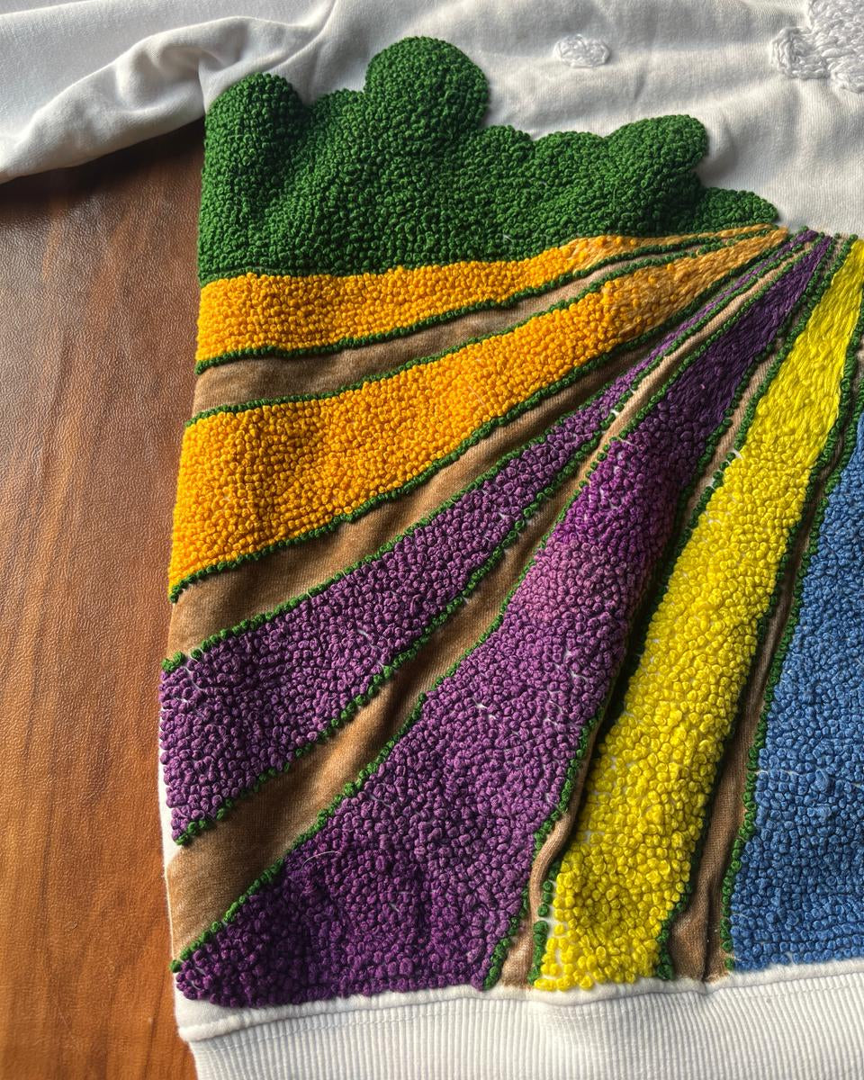 Colorful textured fabric with a geometric pattern hand embroidered on a wooden surface