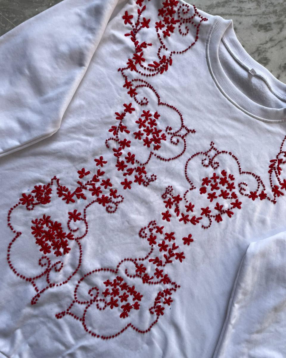 White garment with red floral embroidery on a marble surface