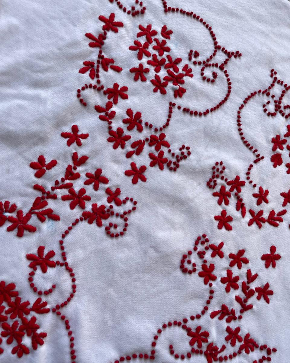 Red floral embroidery on a white fabric background